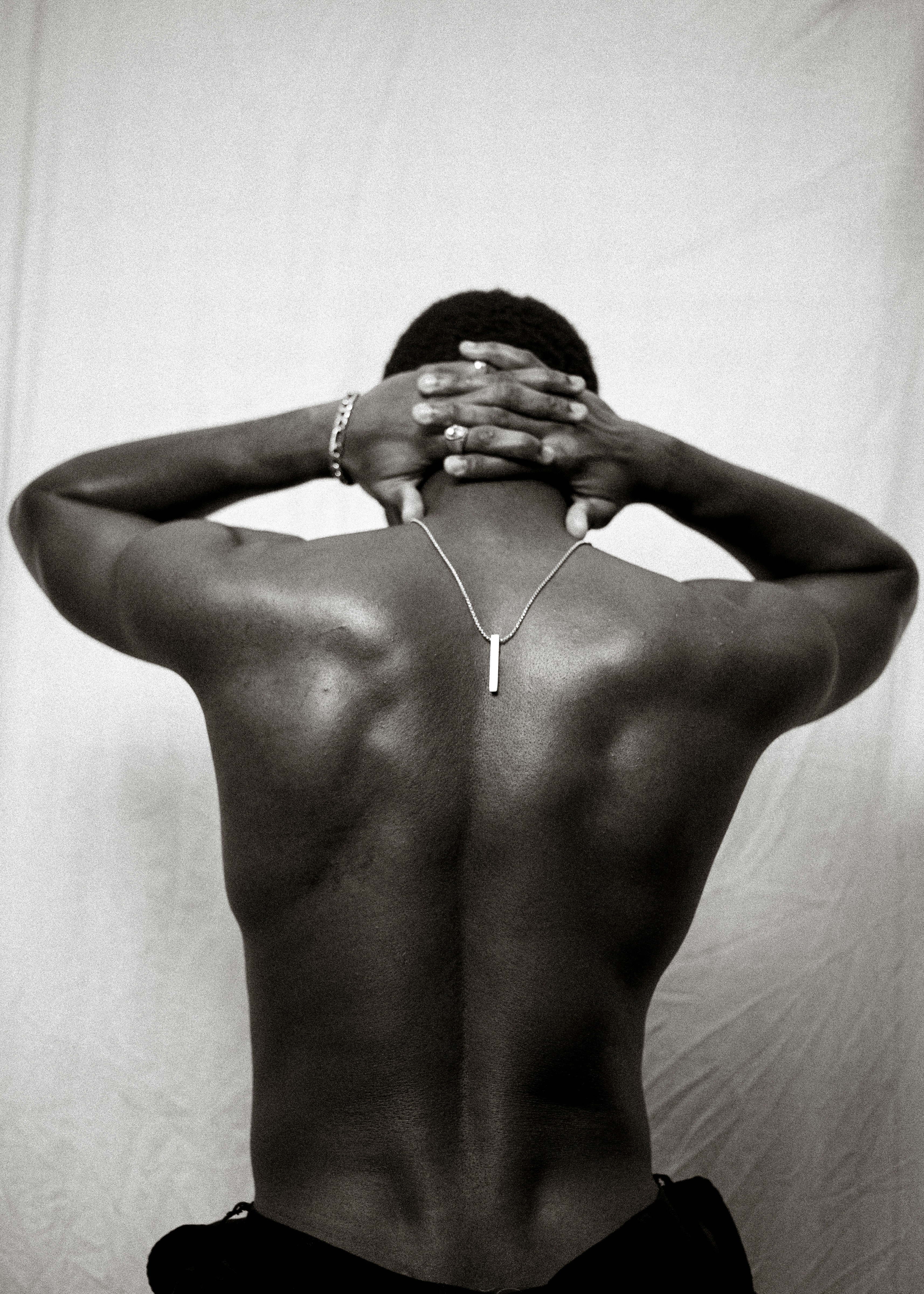 Man with hands behind head showing back muscles