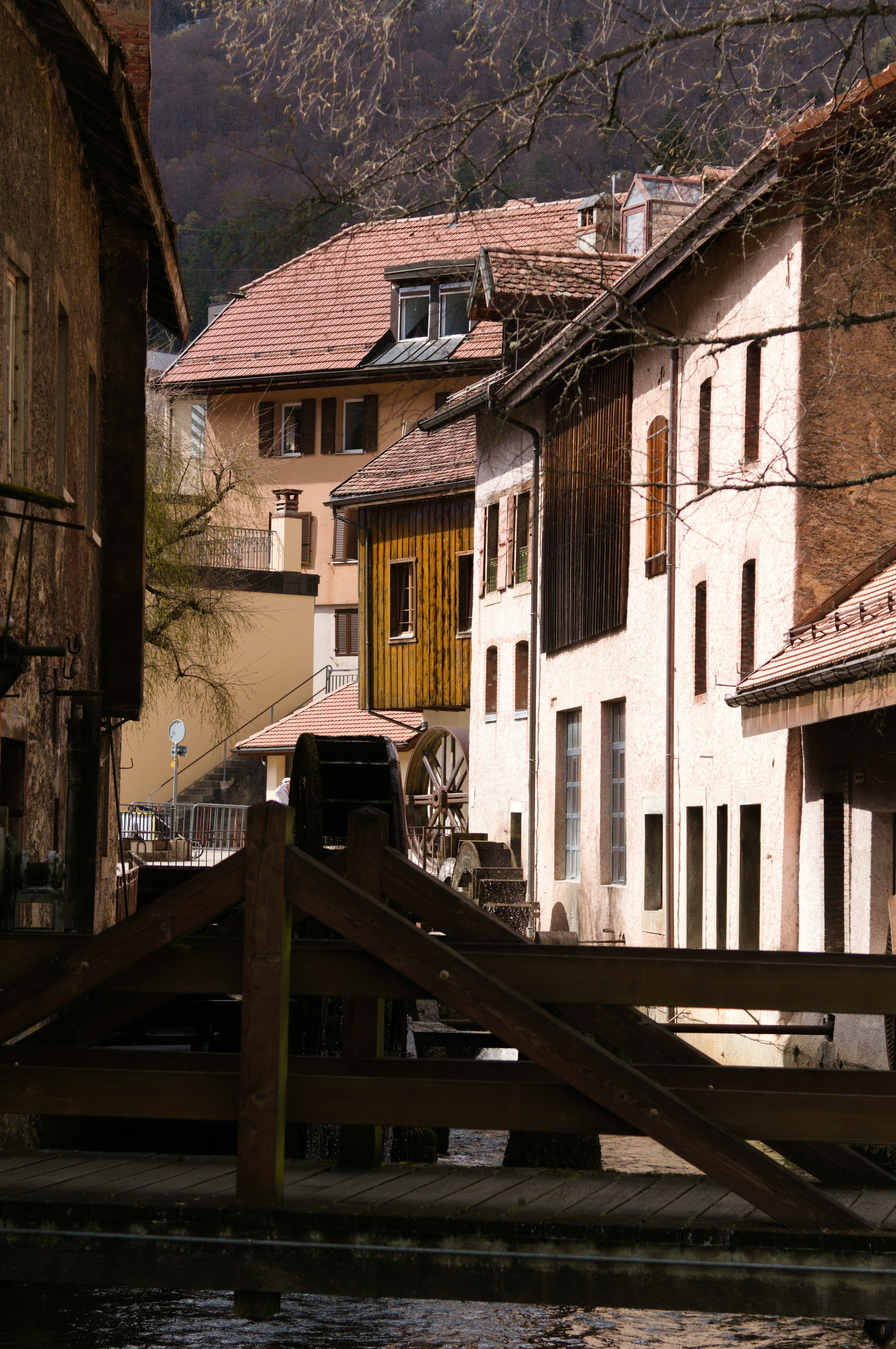 Old european buildings with a water wheel and bridge.