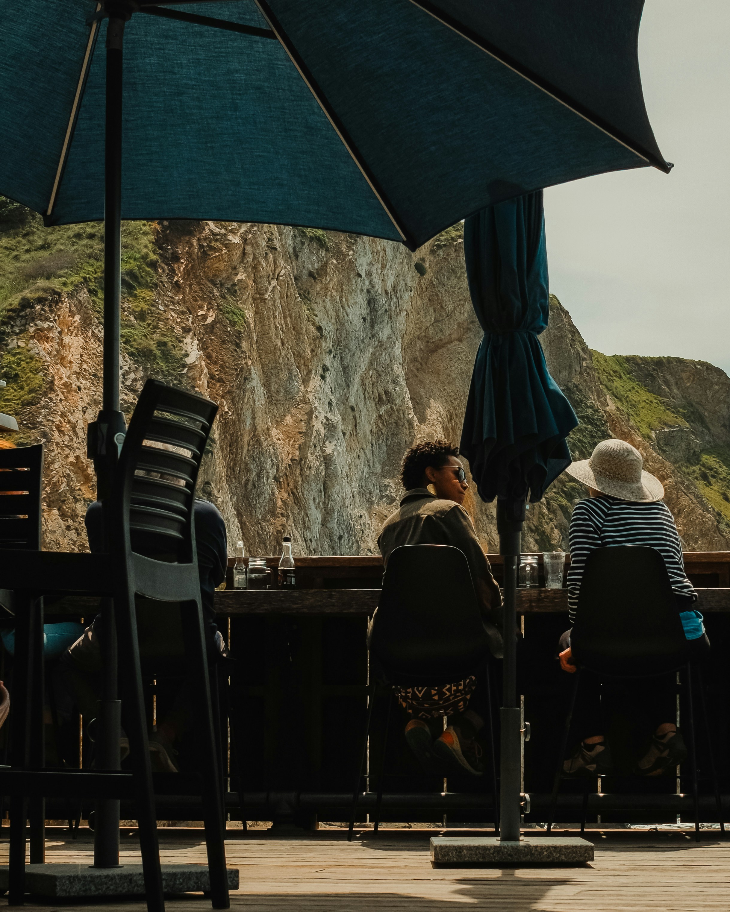 Two people sit at a table overlooking a cliff.
