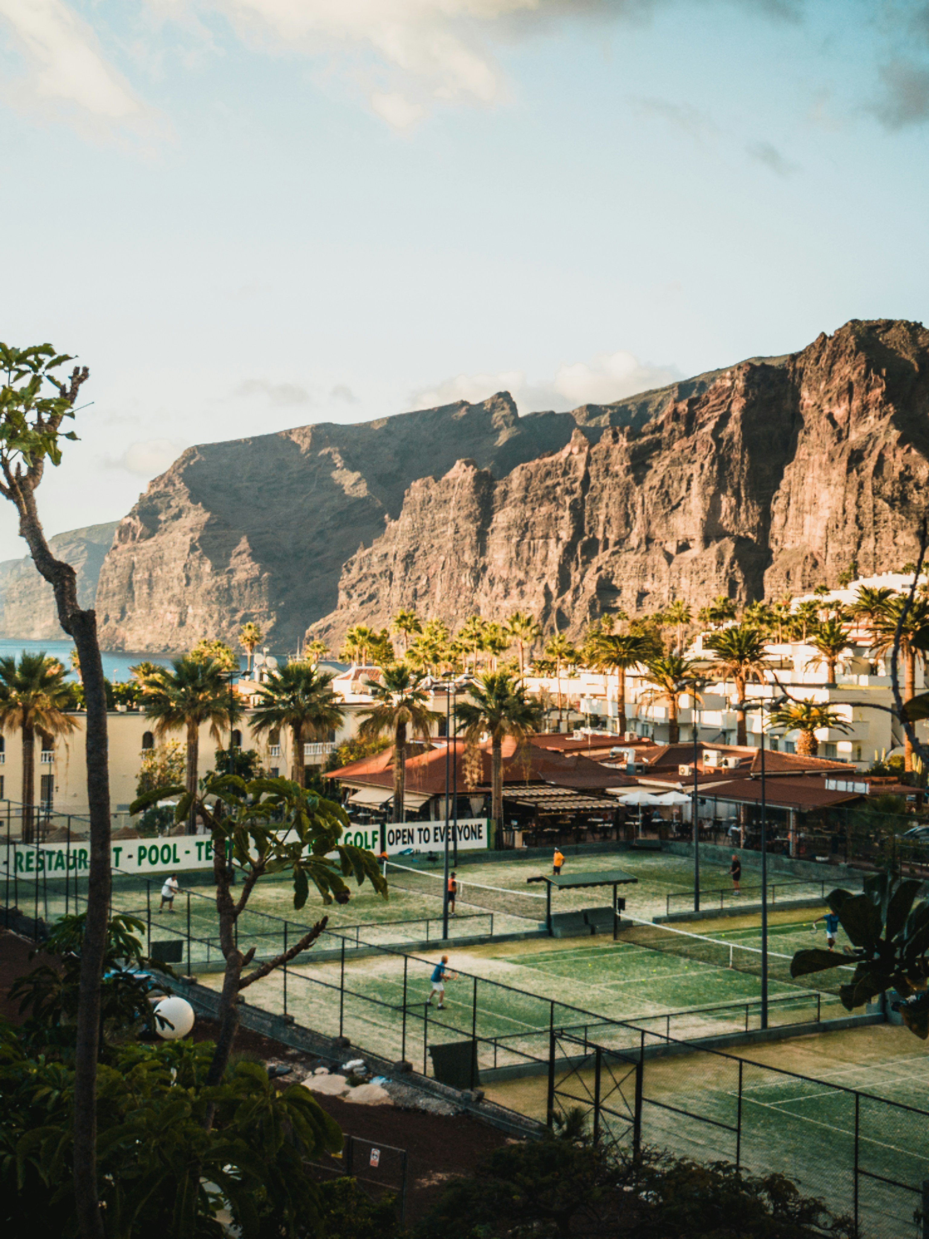 Tennis courts near a resort with rocky cliffs.
