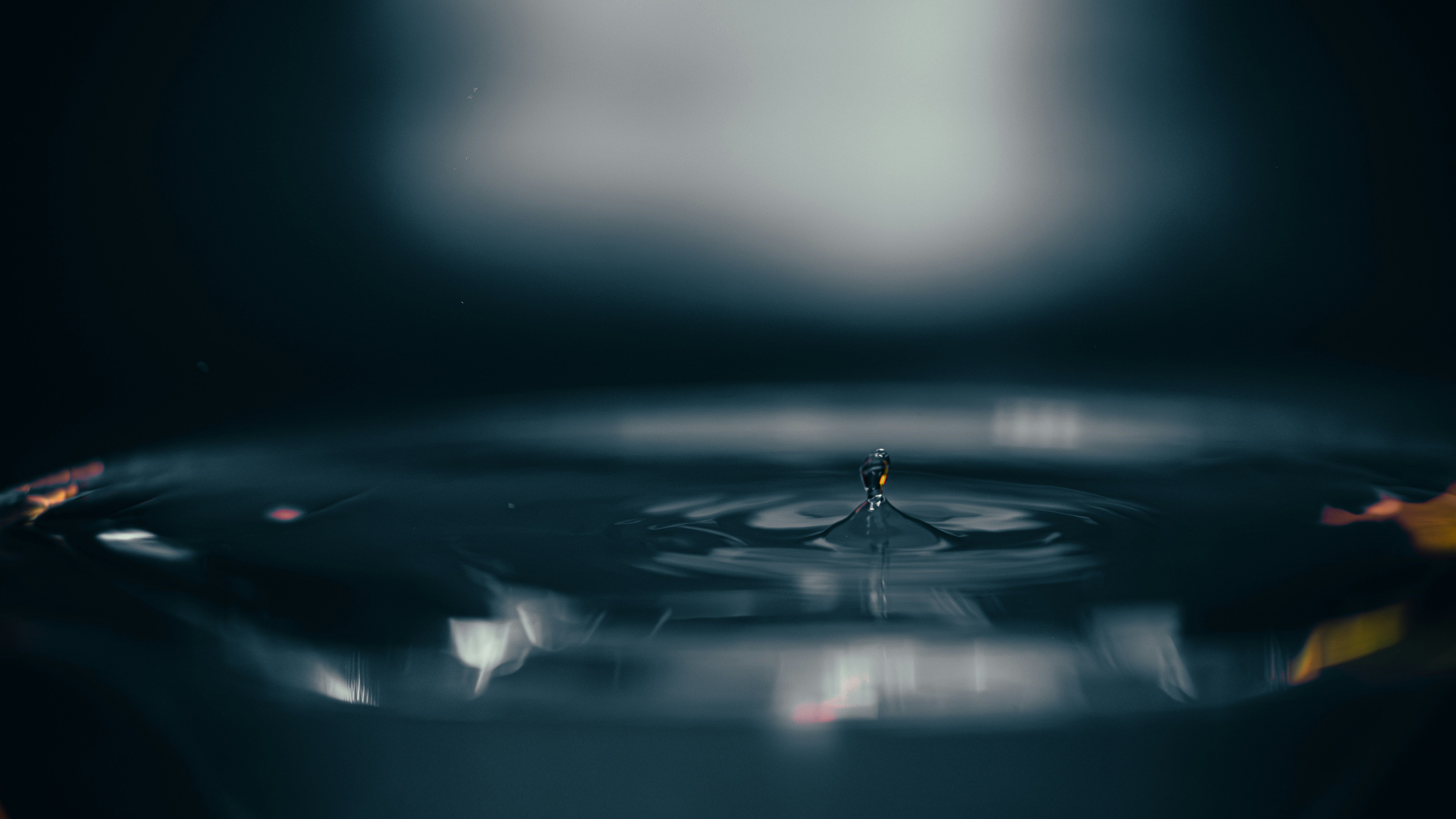 Ein einzelner Wassertropfen, der in ruhiges Wasser fällt.