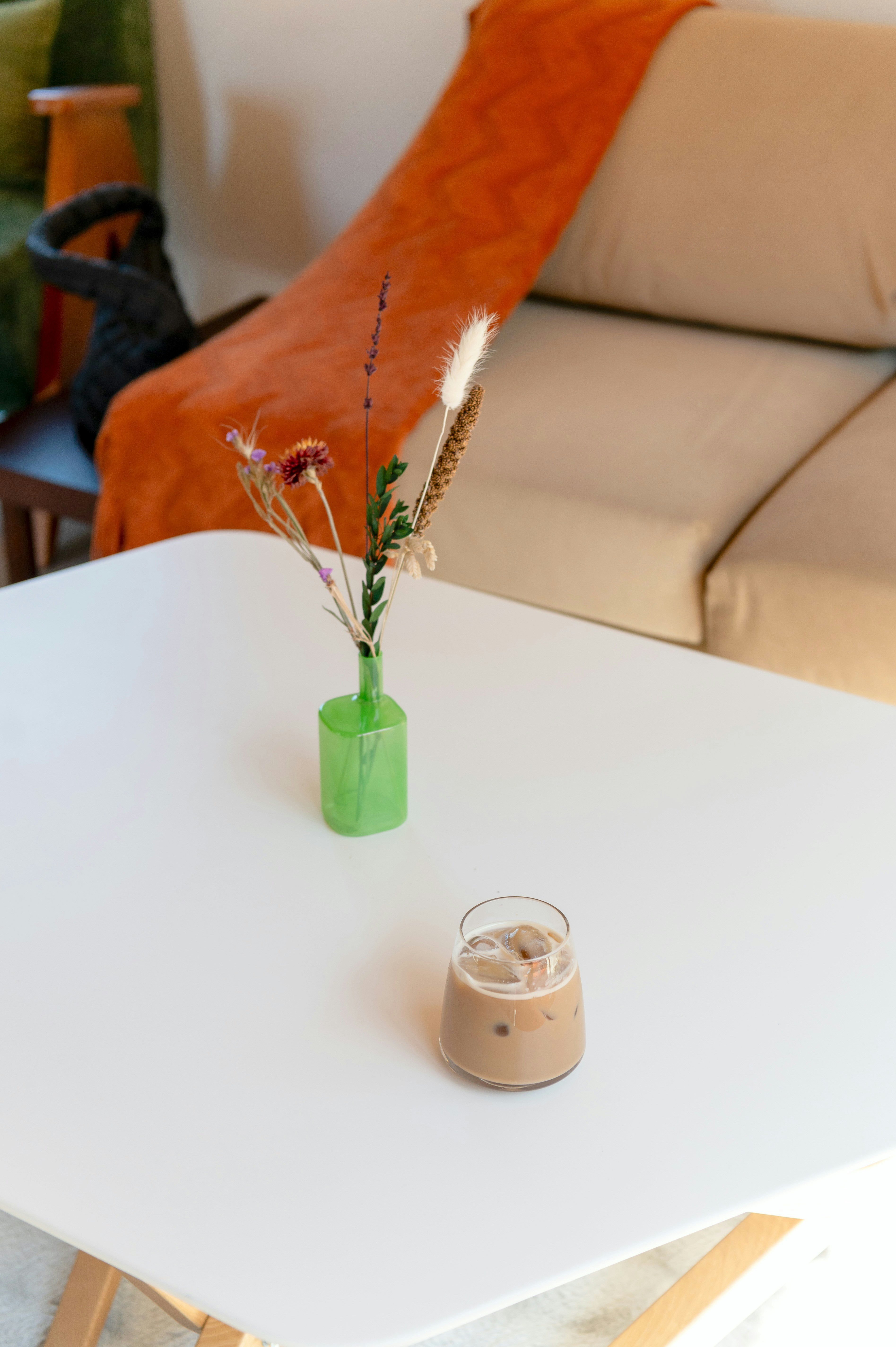 Iced coffee and dried flowers on a white table.