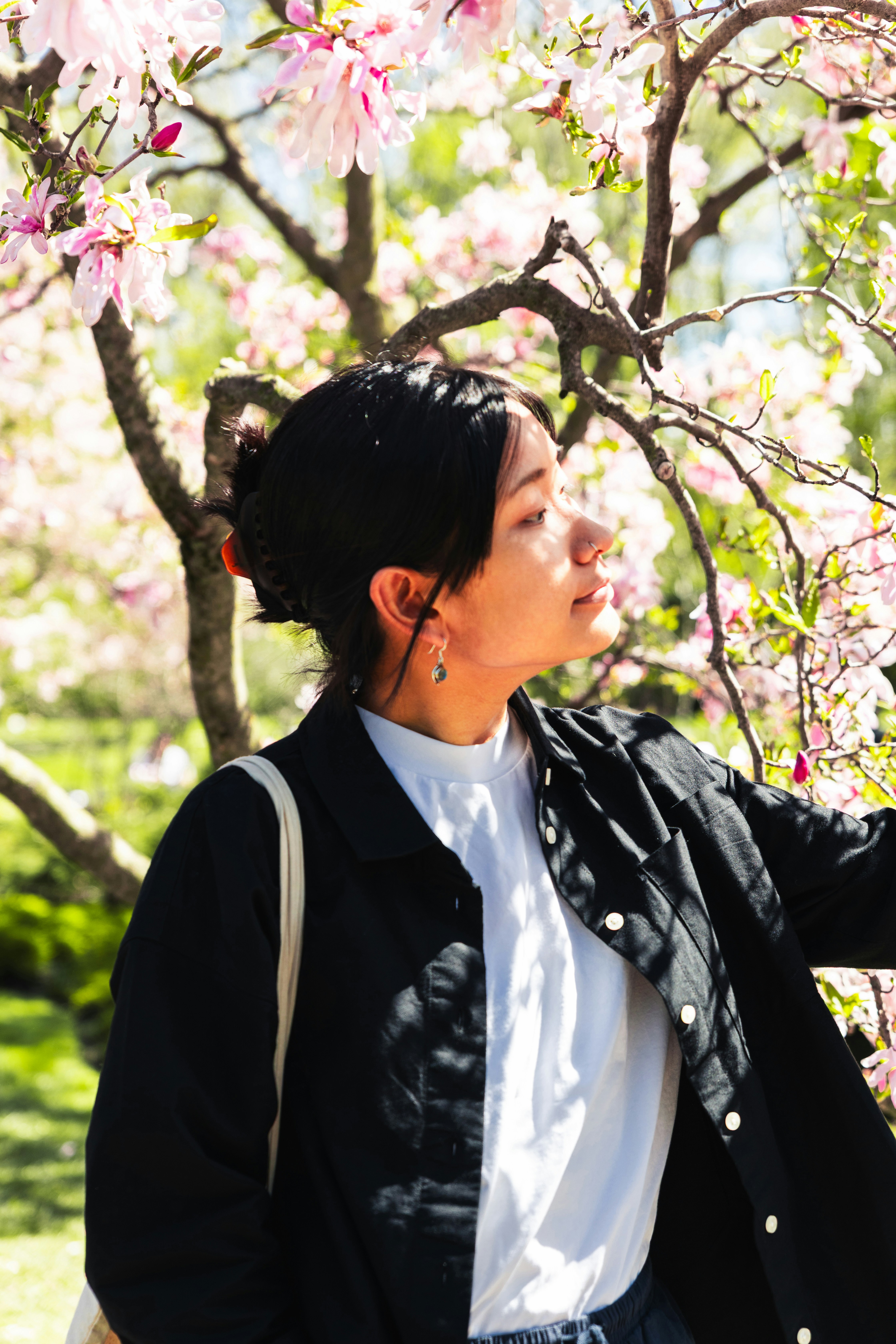 Young woman in a black jacket near blooming tree