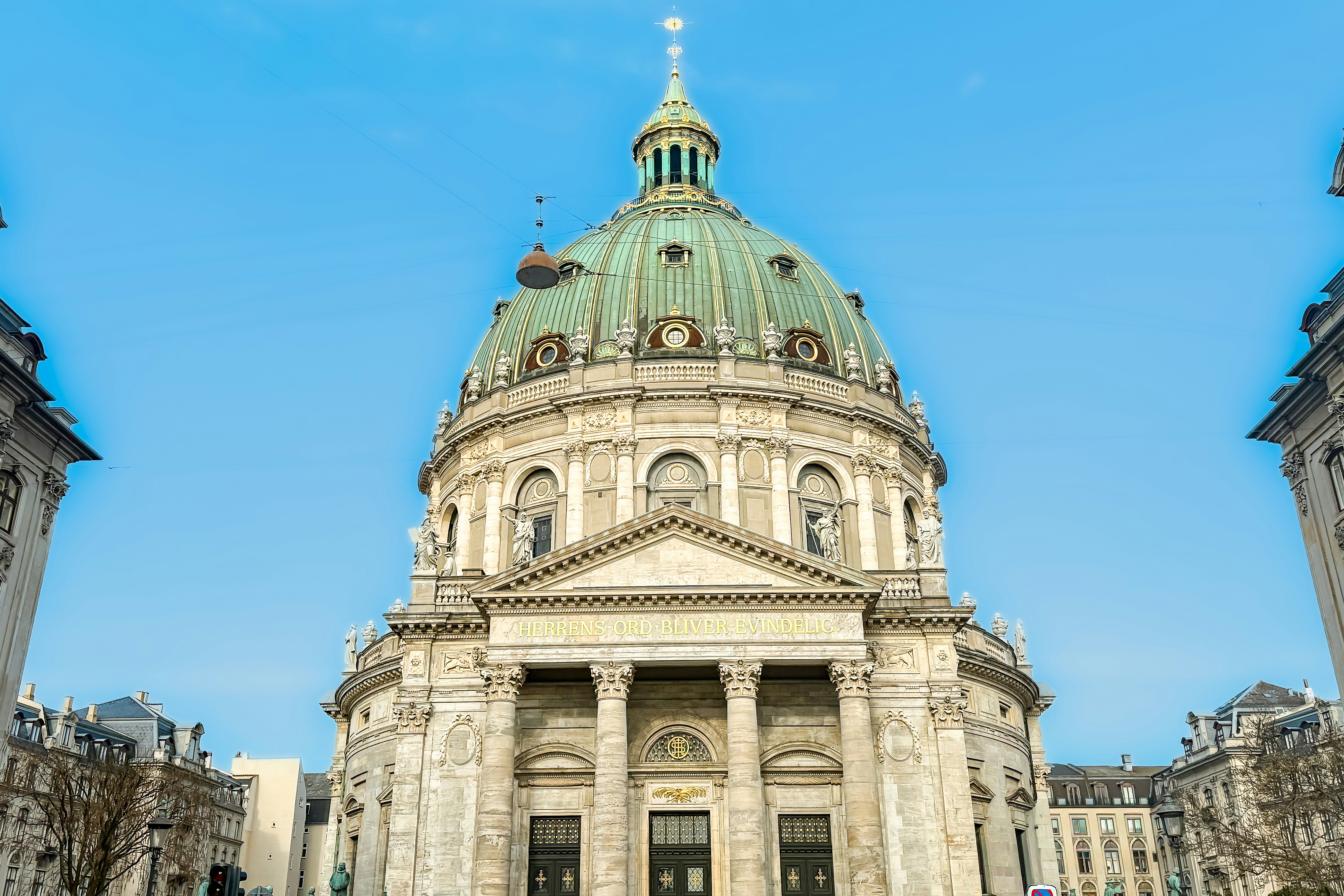 Grand marble building with a green dome under blue sky