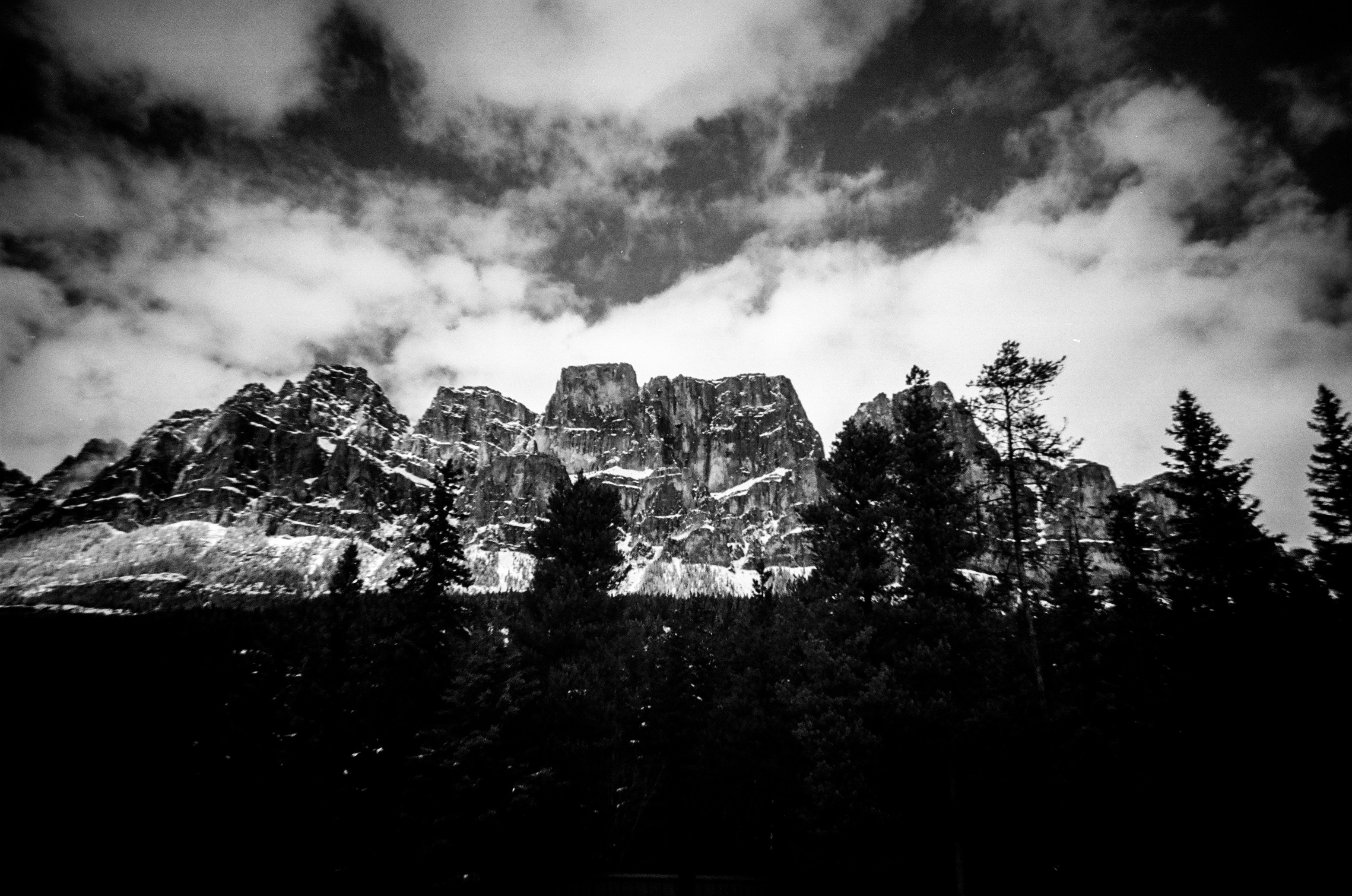 Jagged mountain range with dramatic clouds and pine trees