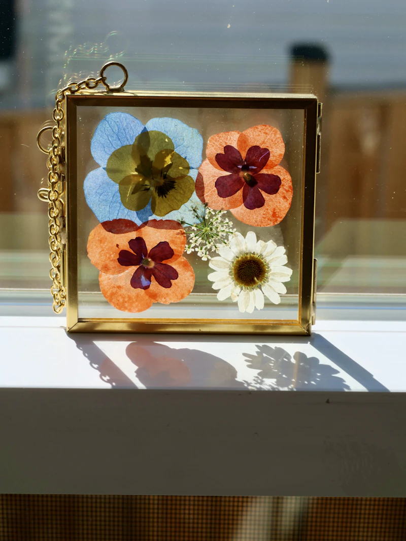 Pressed pansies and wildflowers in a small brass and glass frame
