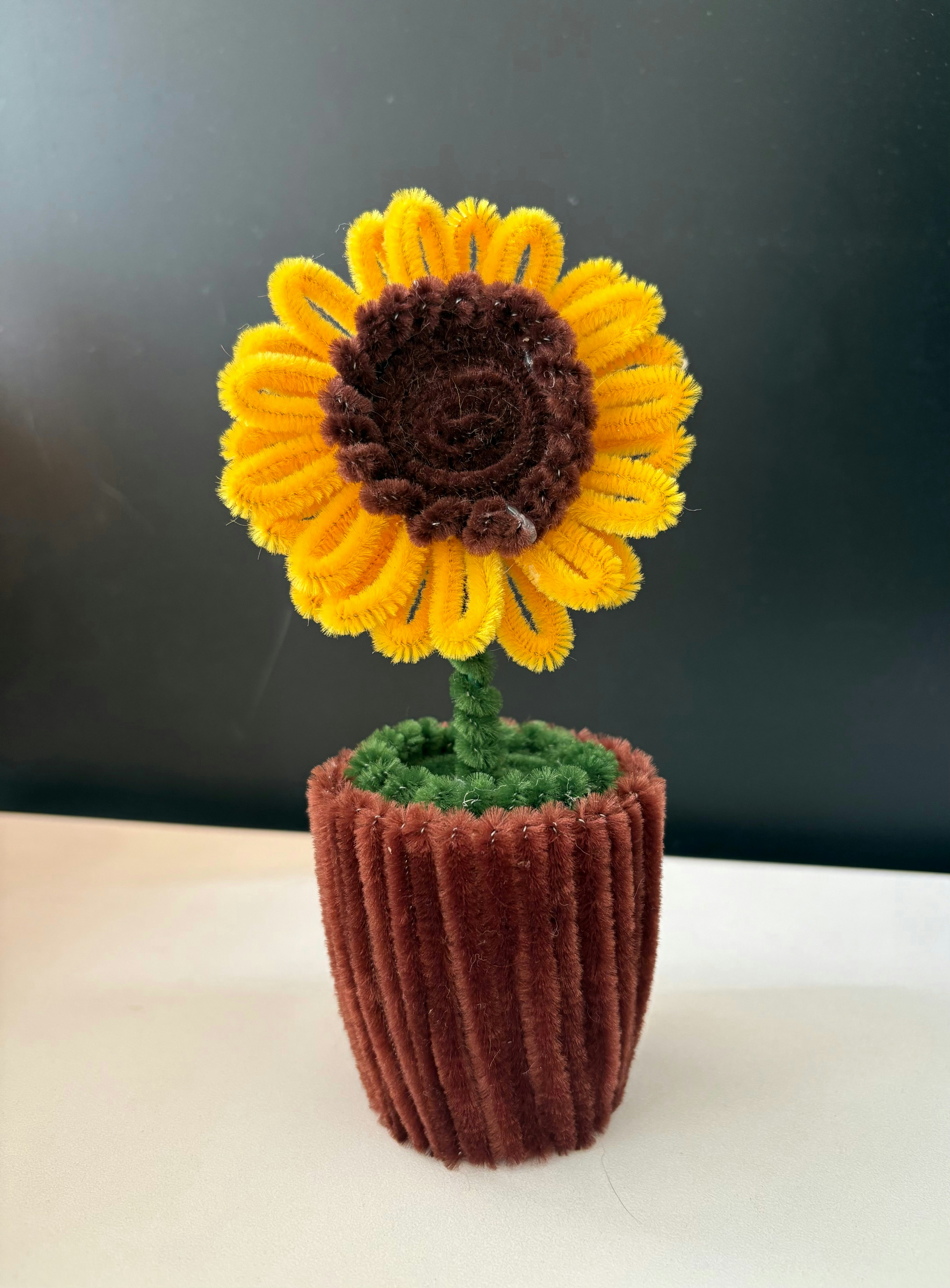 A sunflower made from pipe cleaners in a pot
