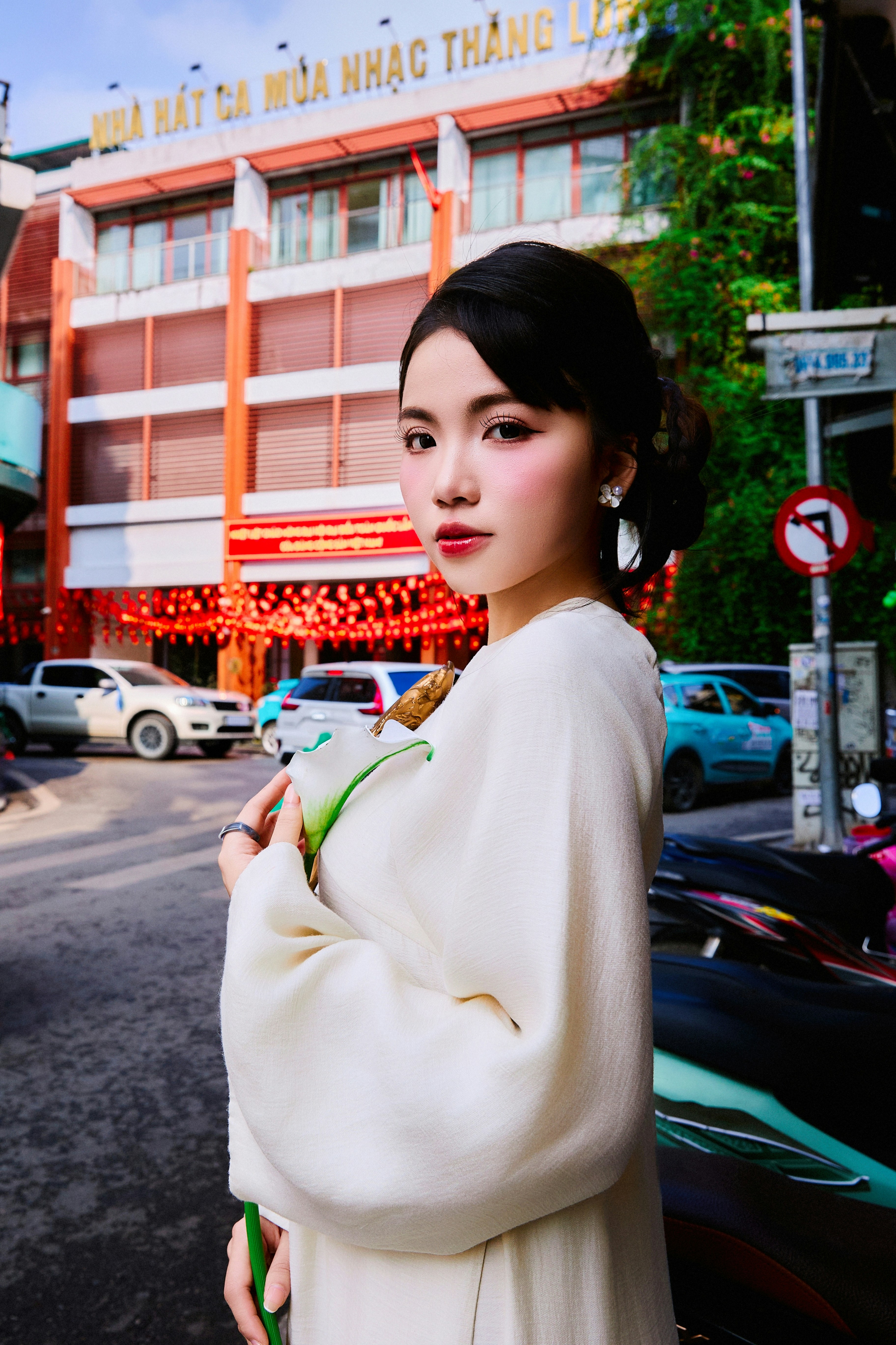 Young woman in white dress holding a flower on street