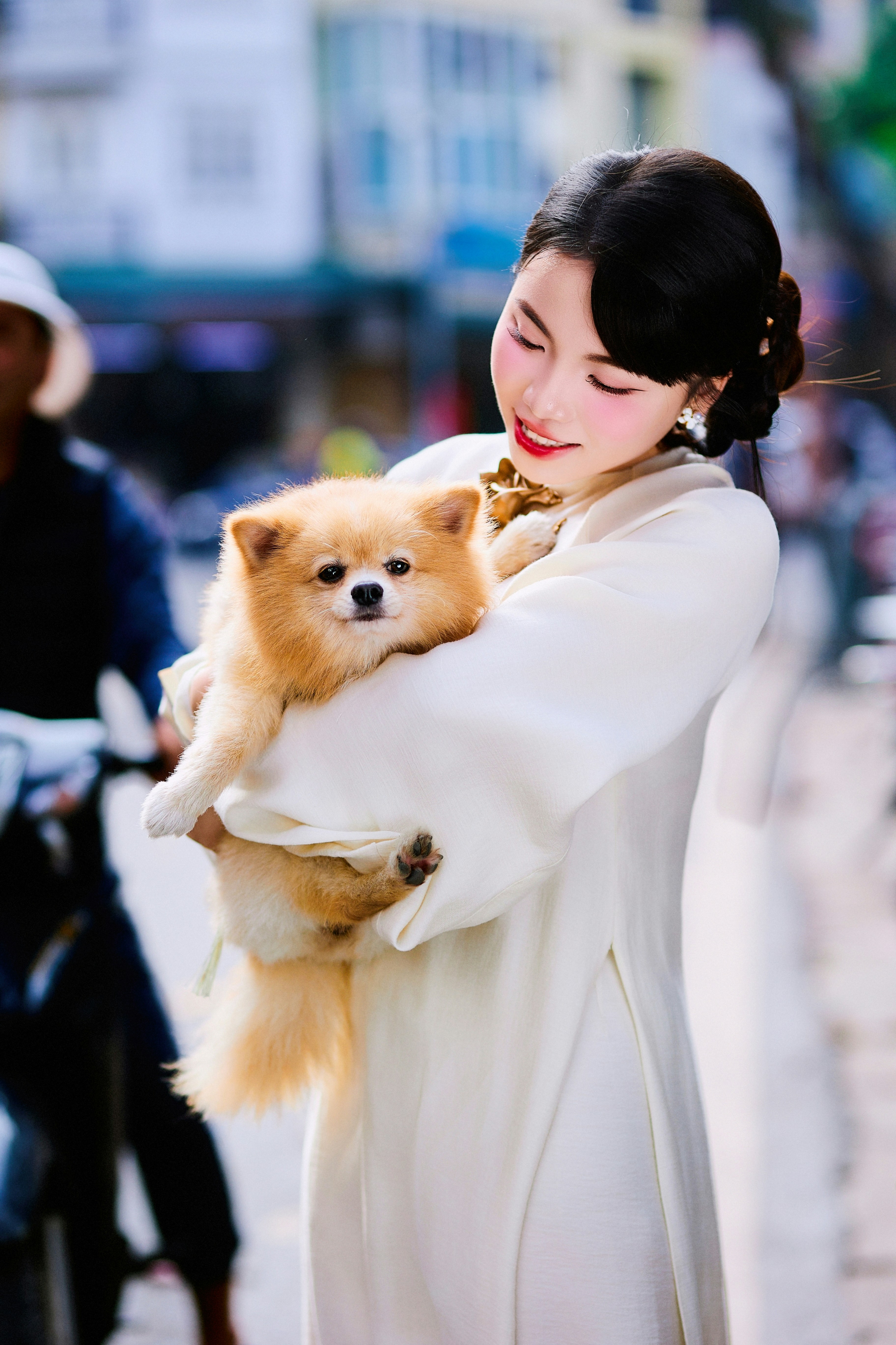 Woman in traditional dress holding a fluffy pomeranian dog