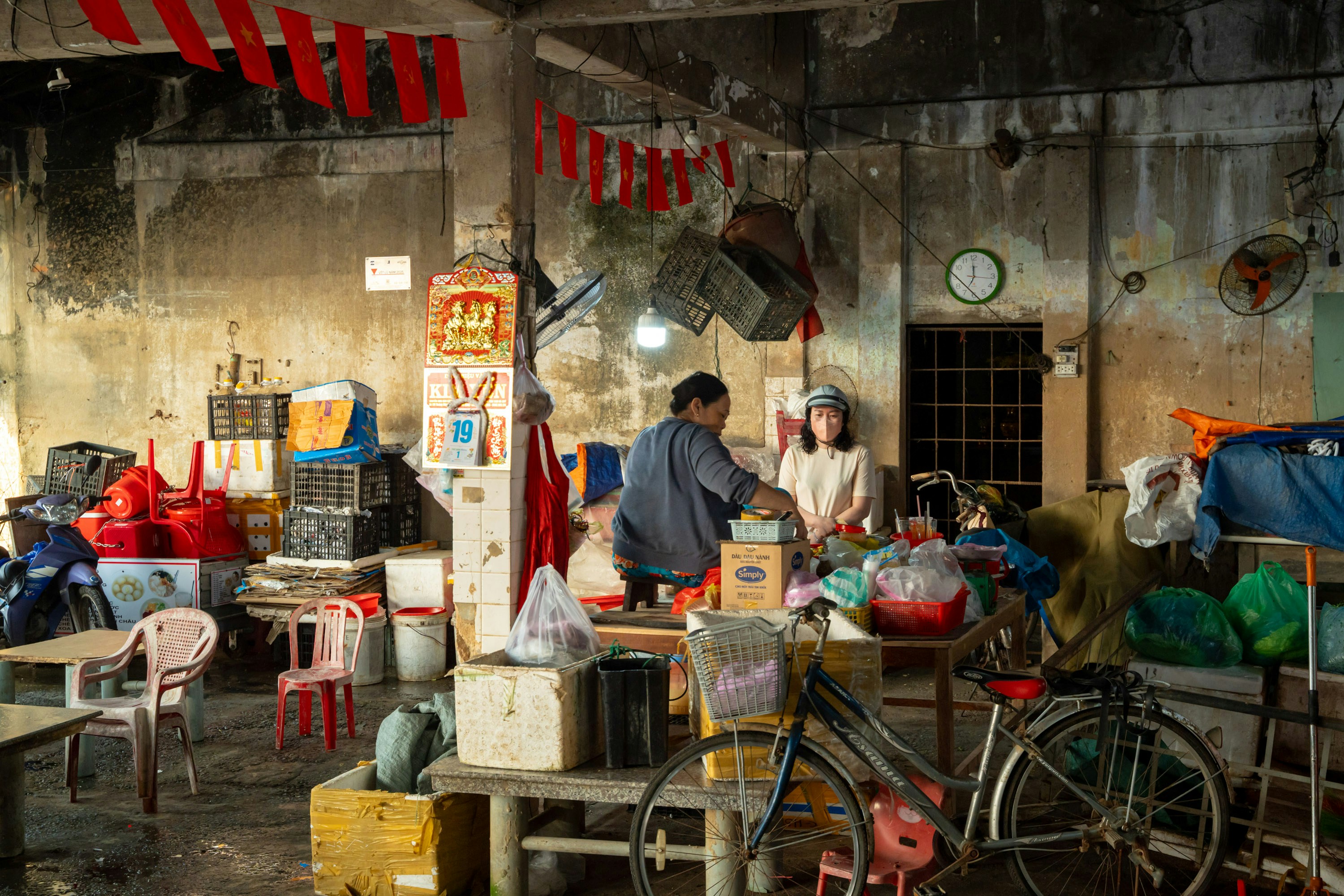 Two people in a cluttered shop with many items.