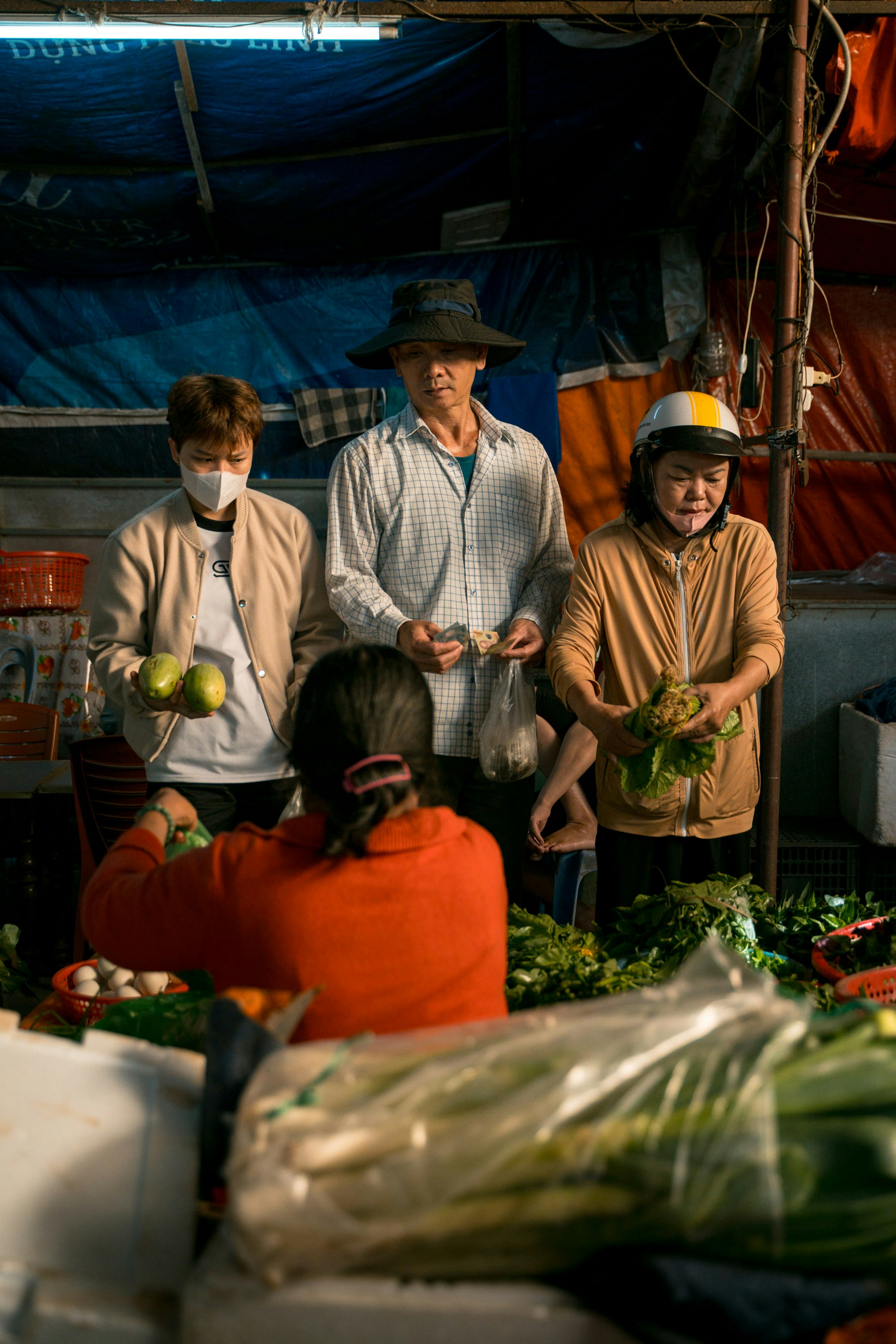 People buying and selling produce at a market stall.