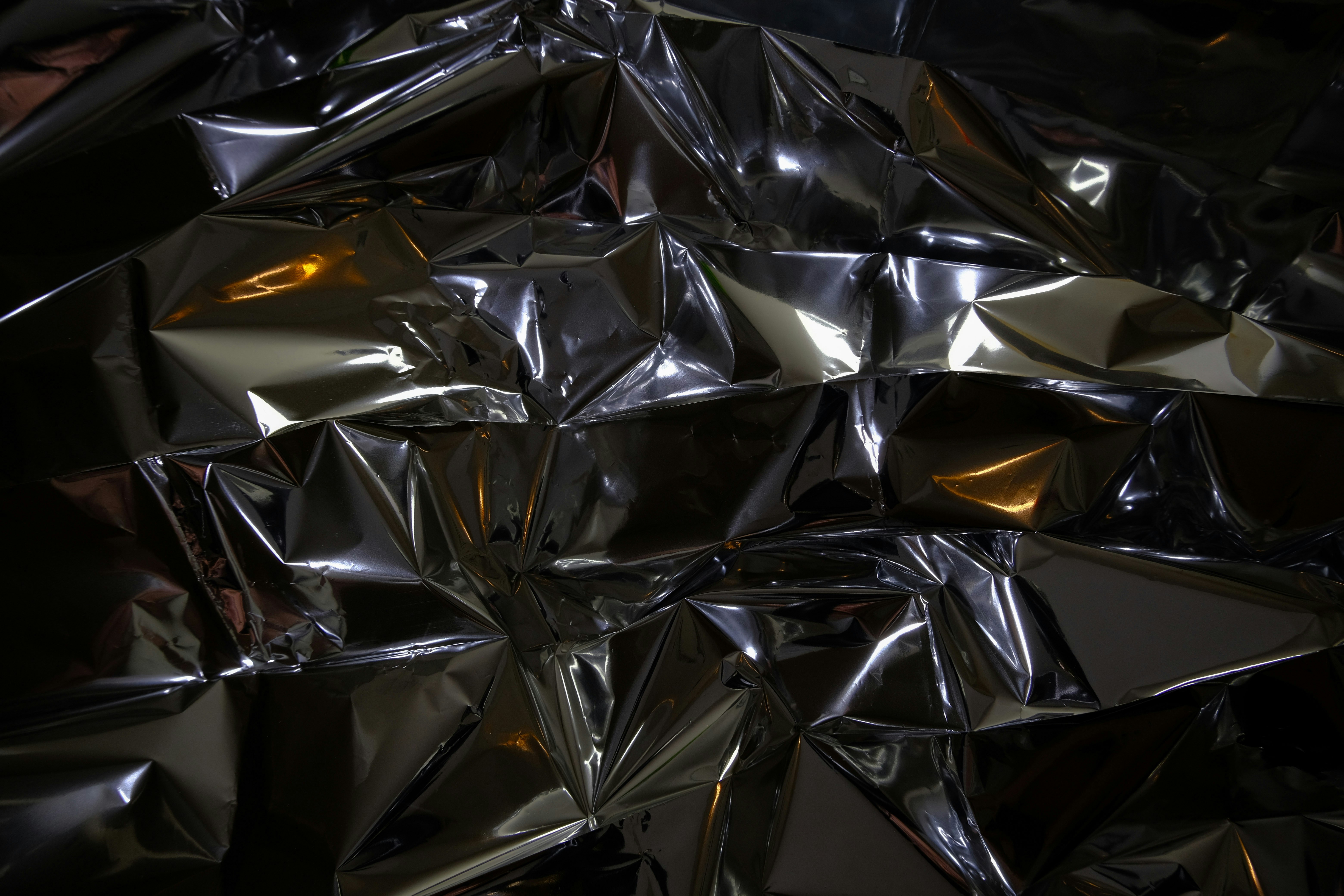 Crinkled metallic surface reflecting light and color.