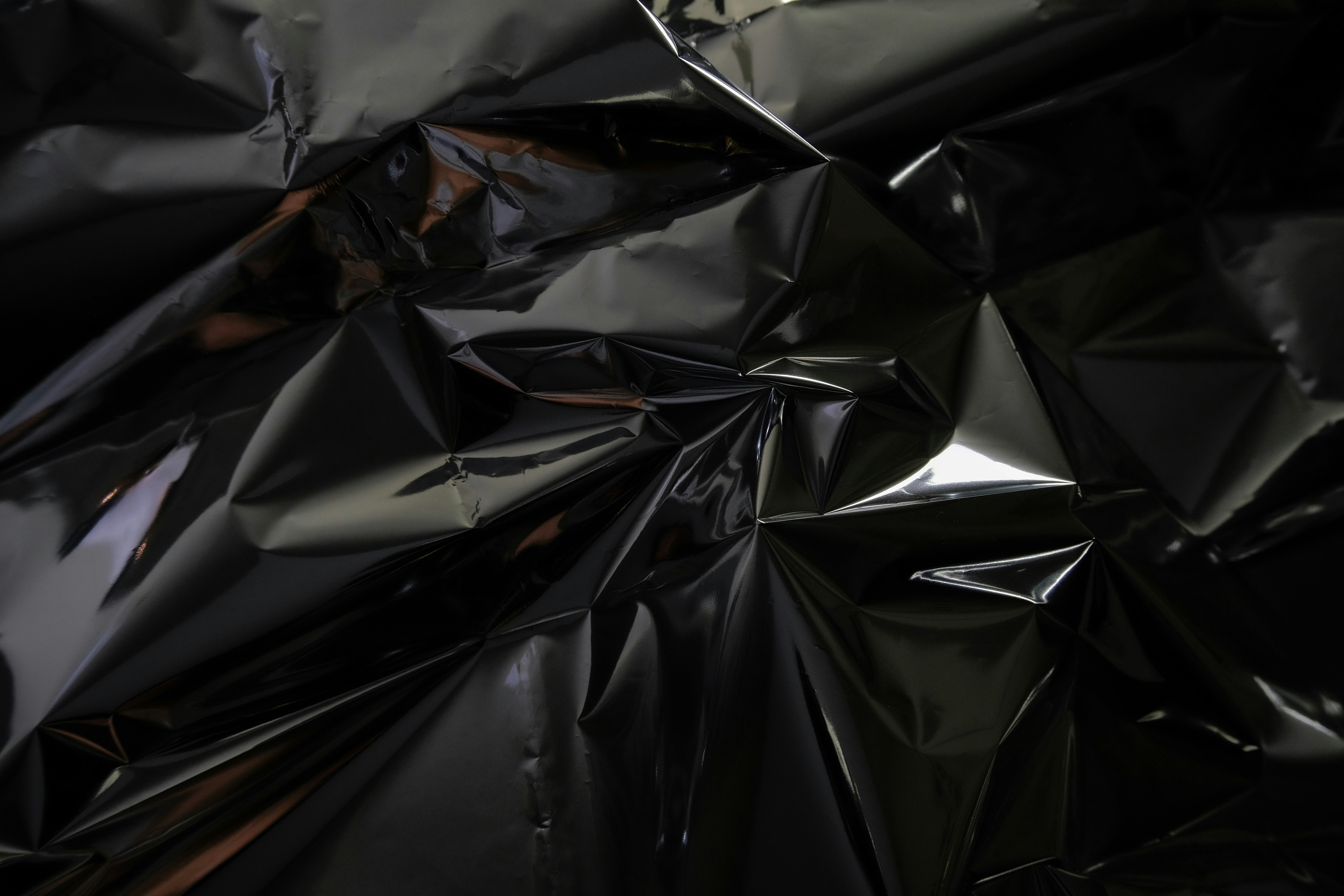 Crumpled black metallic material with reflections