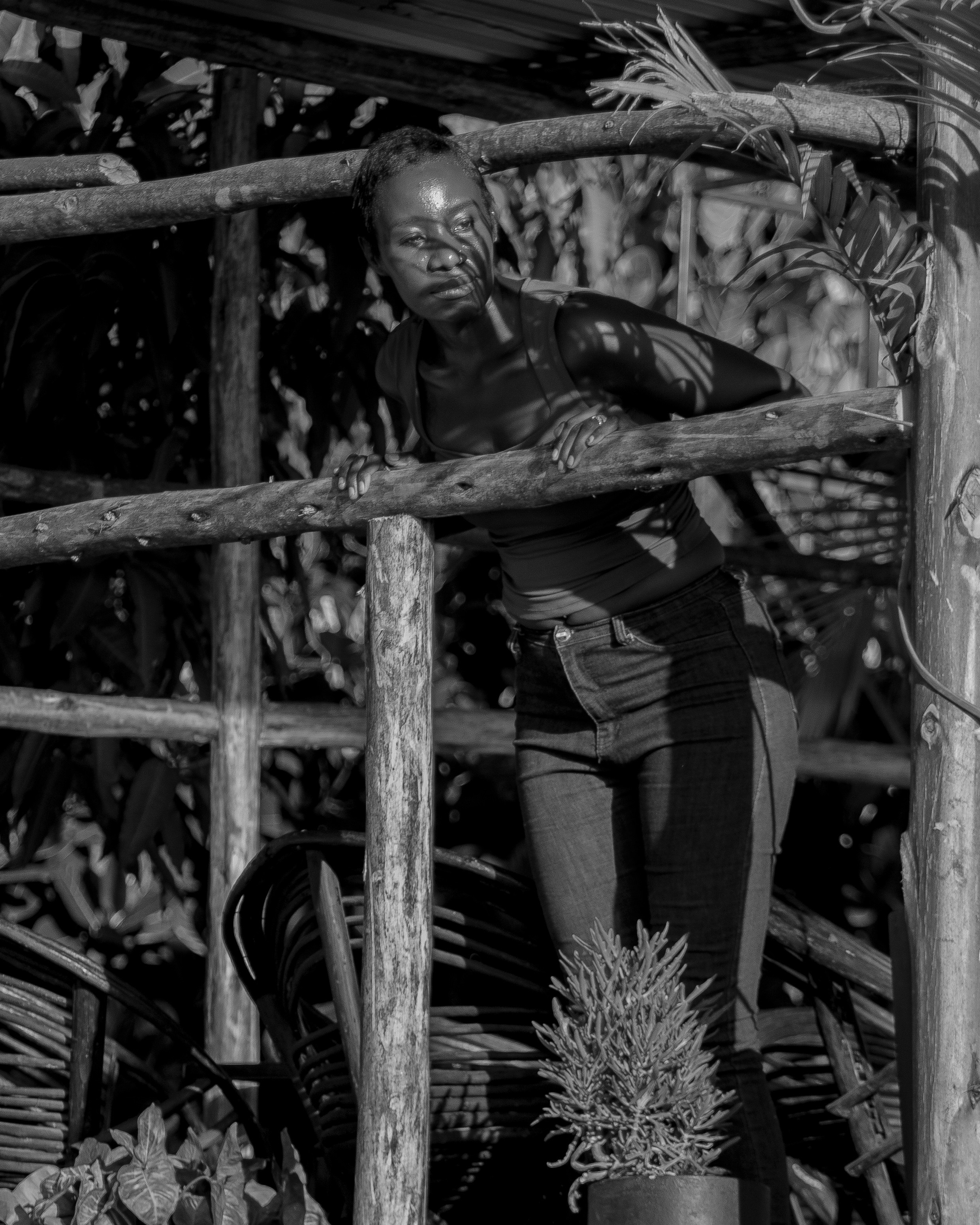 Femme appuyée sur une rambarde en bois avec une lumière tachetée