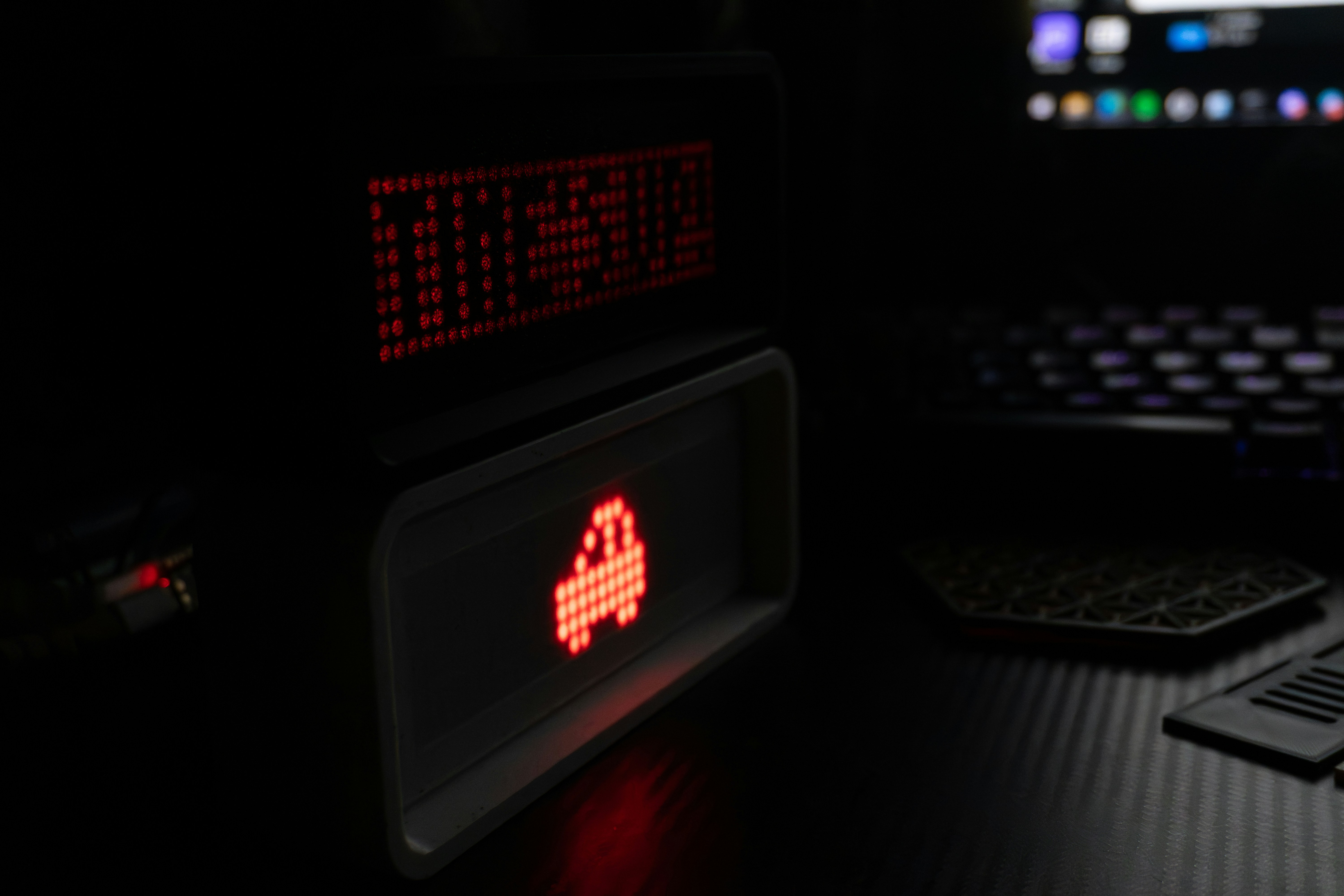 Retro digital alarm clock displaying pixelated car.