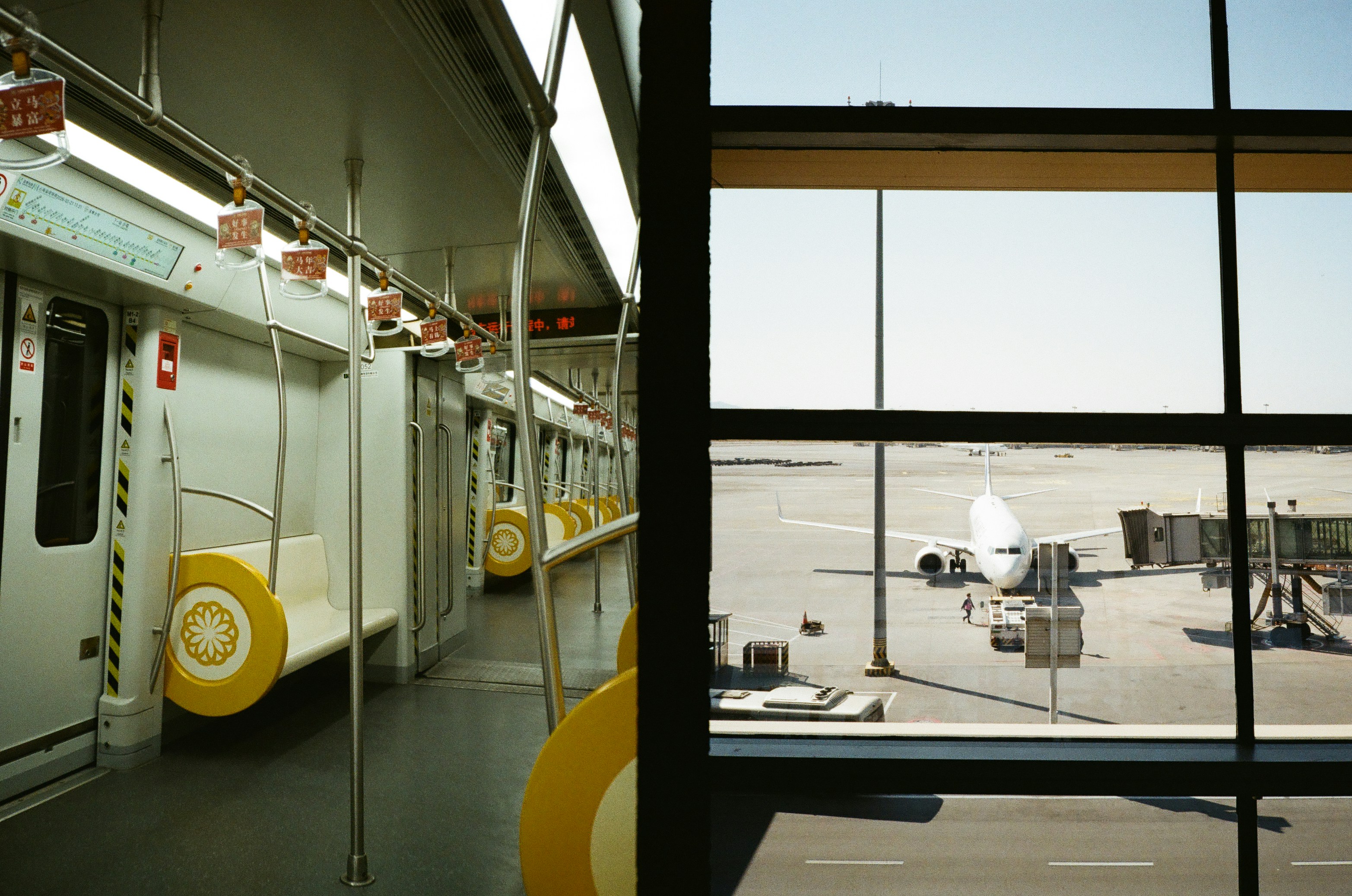 Inside a subway car looking out at an airport tarmac