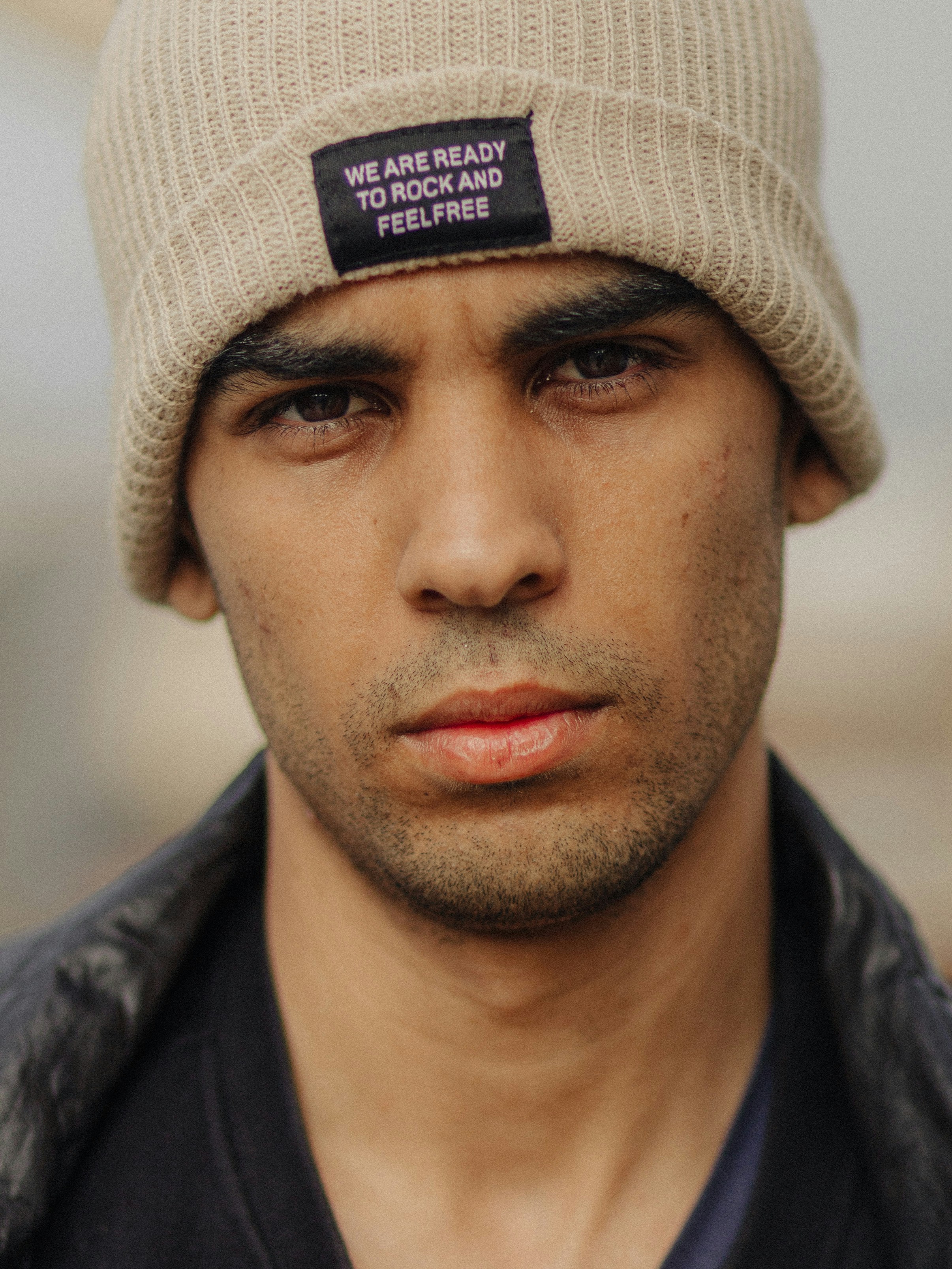 Young man wearing a beige beanie with text