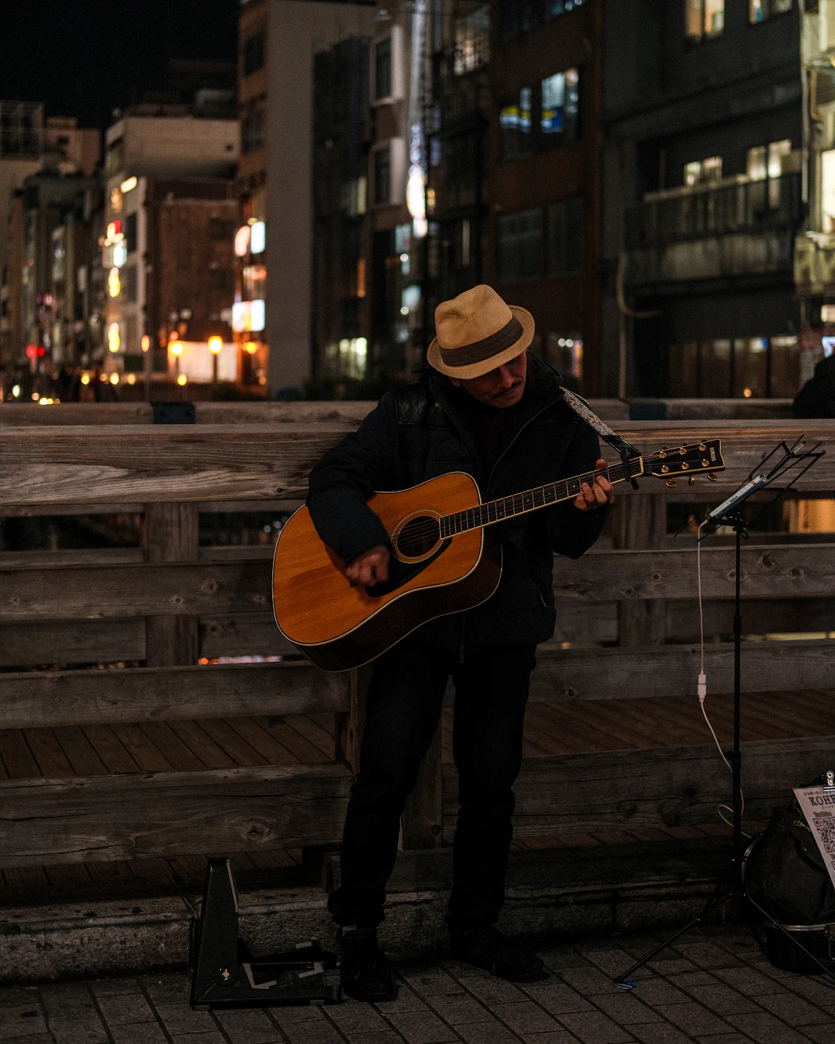 Busker playing guitar on a city street at night