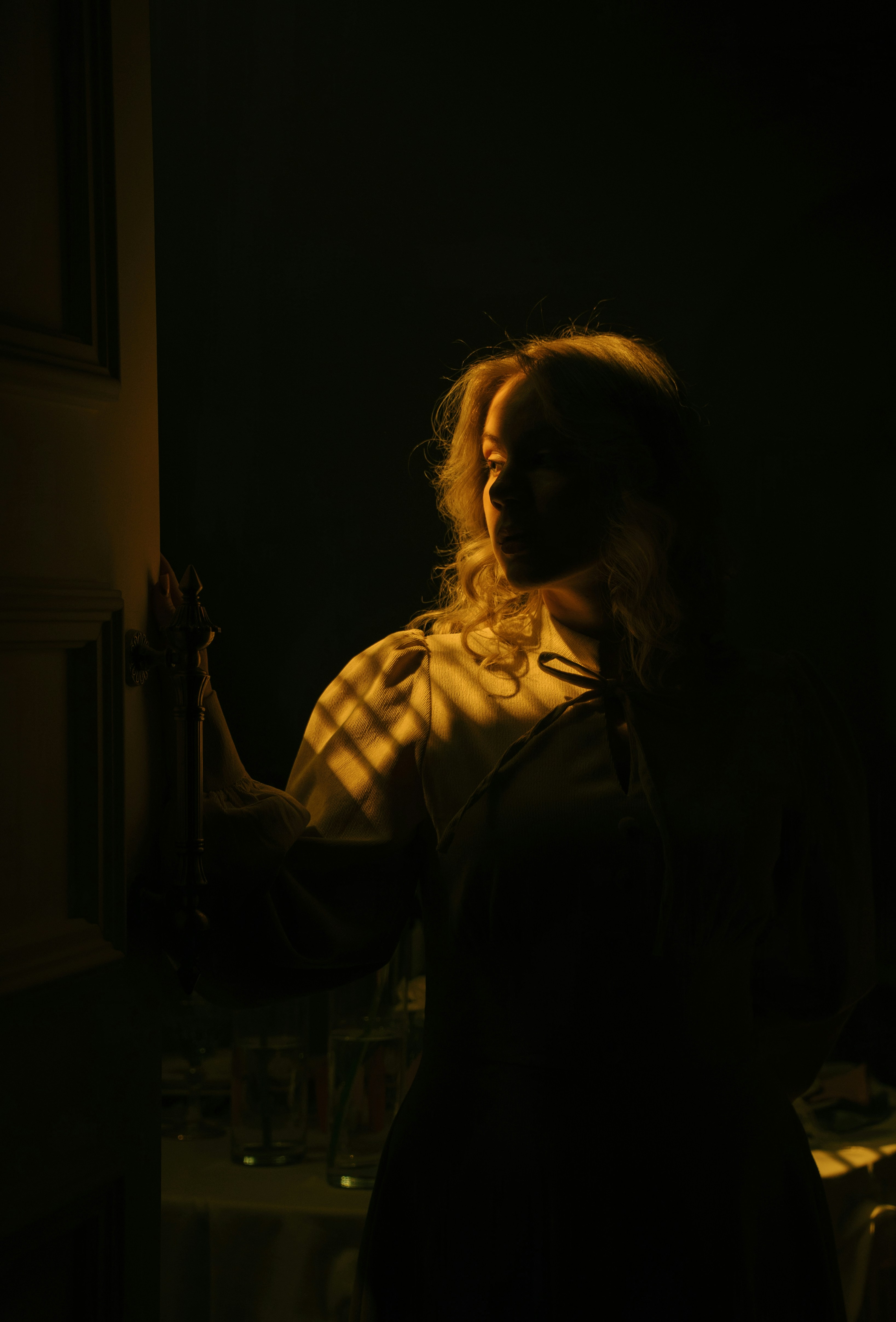 Woman illuminated by light through blinds