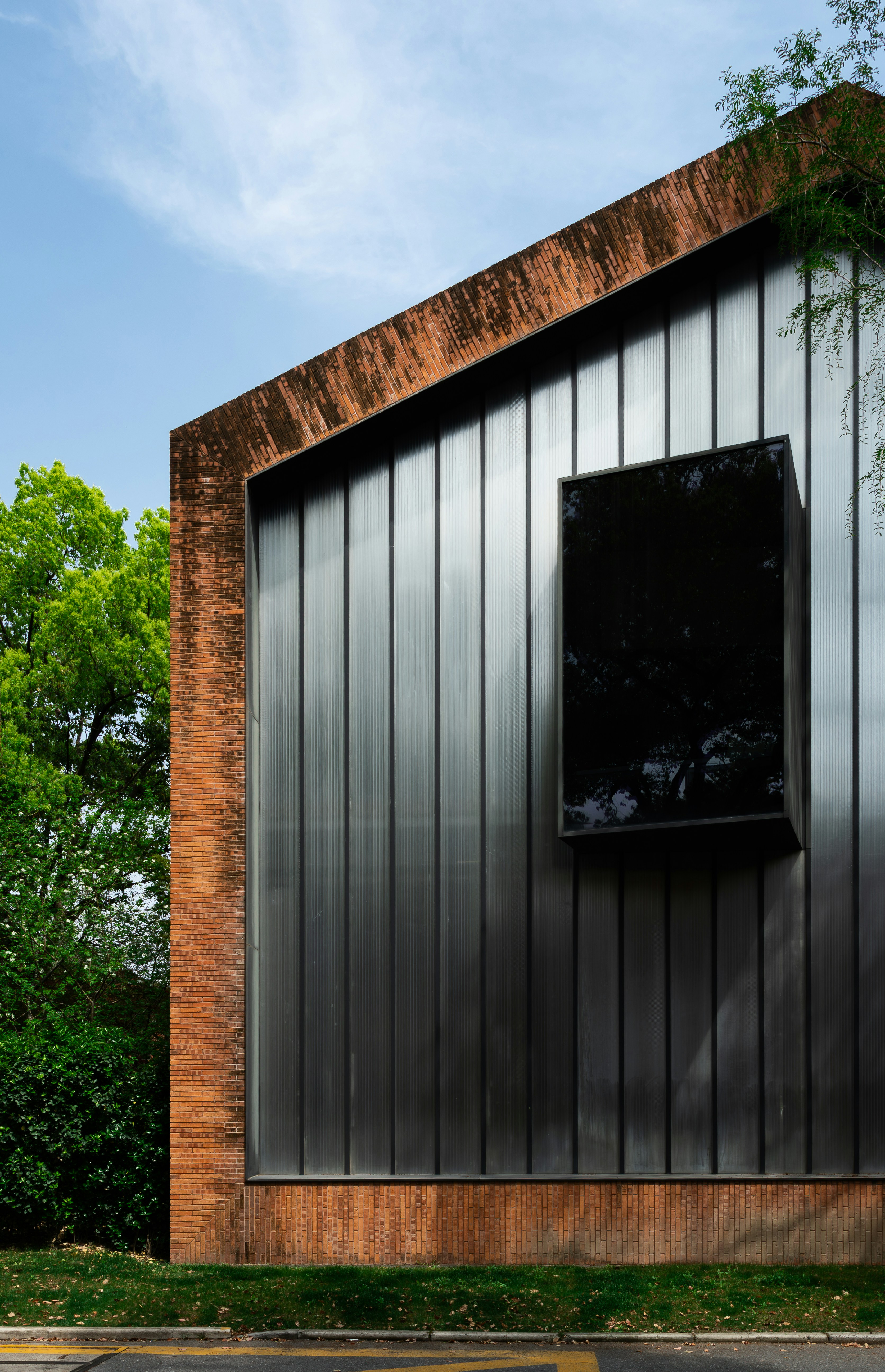 현대적인 벽돌과 금속 건물에 어두운 창문이 있습니다.