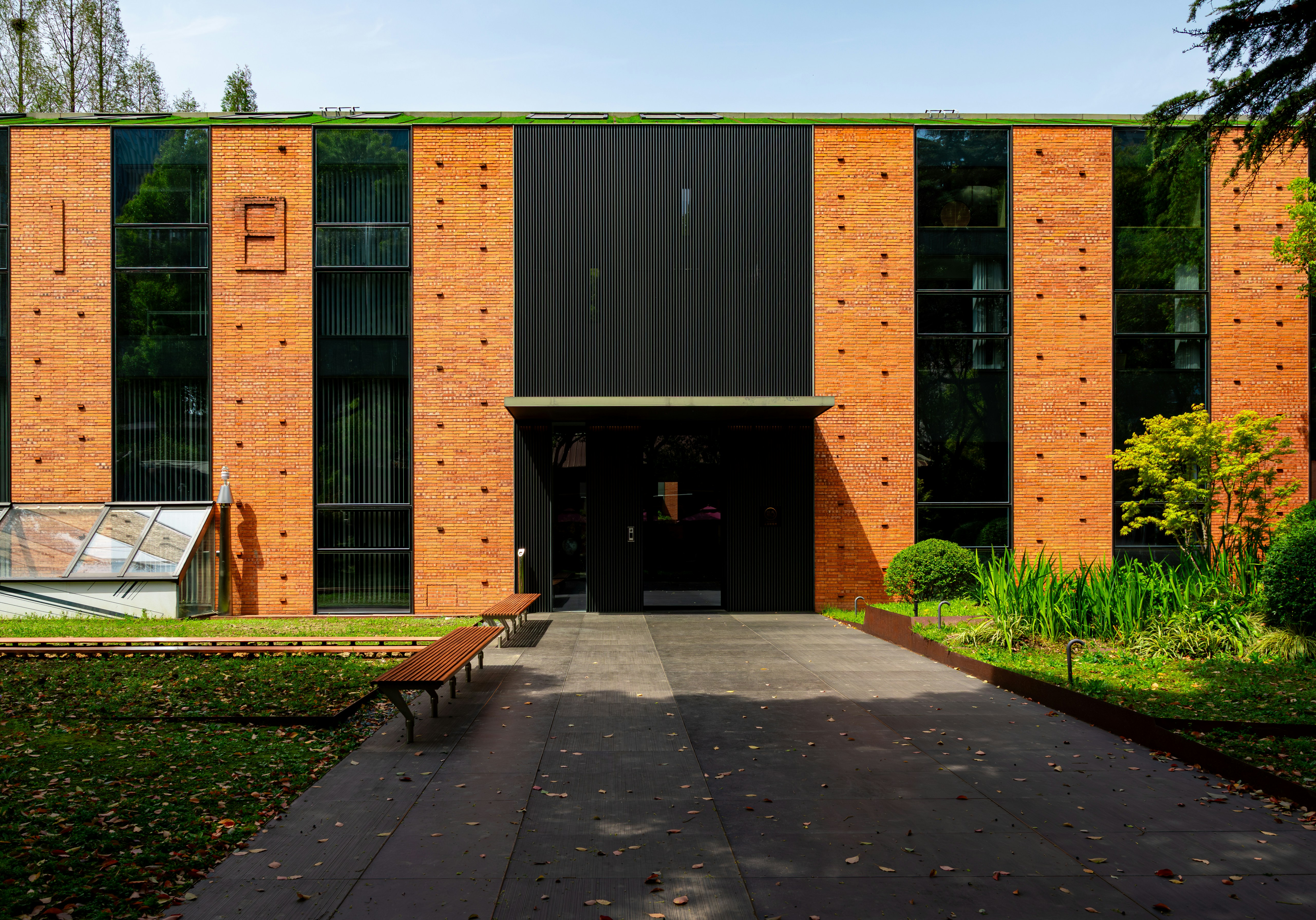 Modern brick and black-framed public building behind a garden path