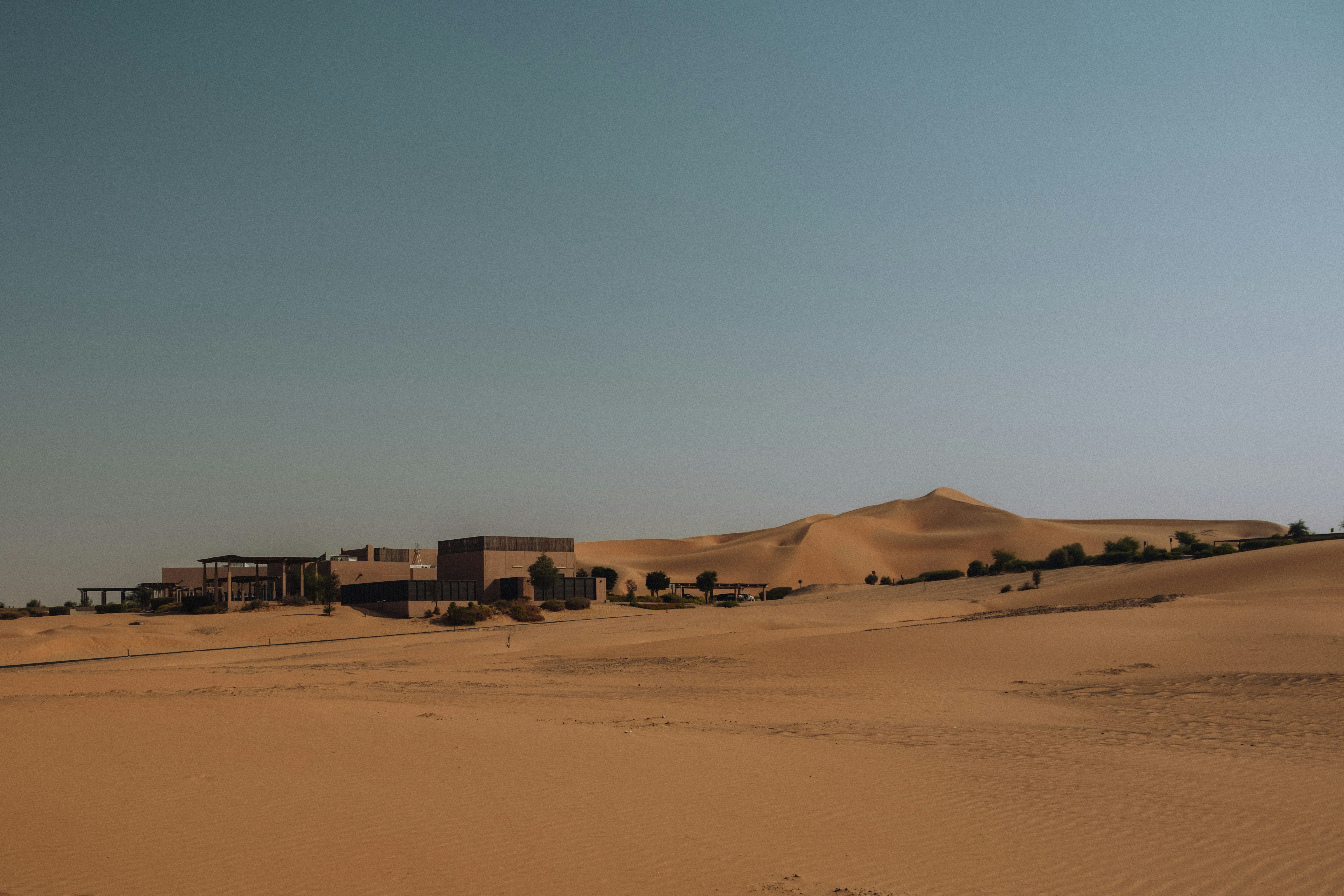 Edifici incastonati tra dune di sabbia sotto un cielo limpido.