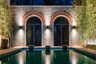 Two arched doorways with bamboo flanking a reflective pool.