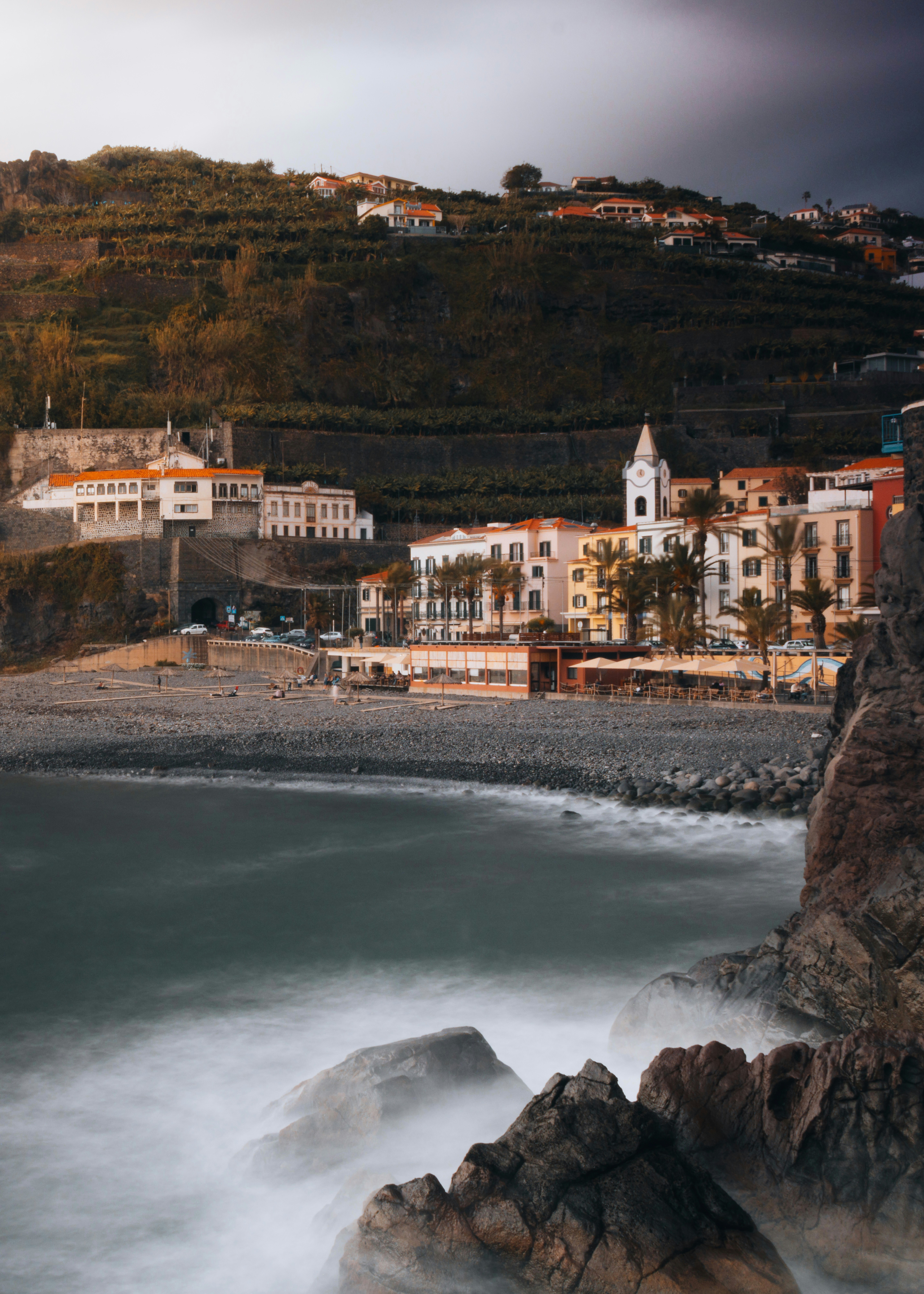 Coastal town with buildings on a hill overlooking the sea.