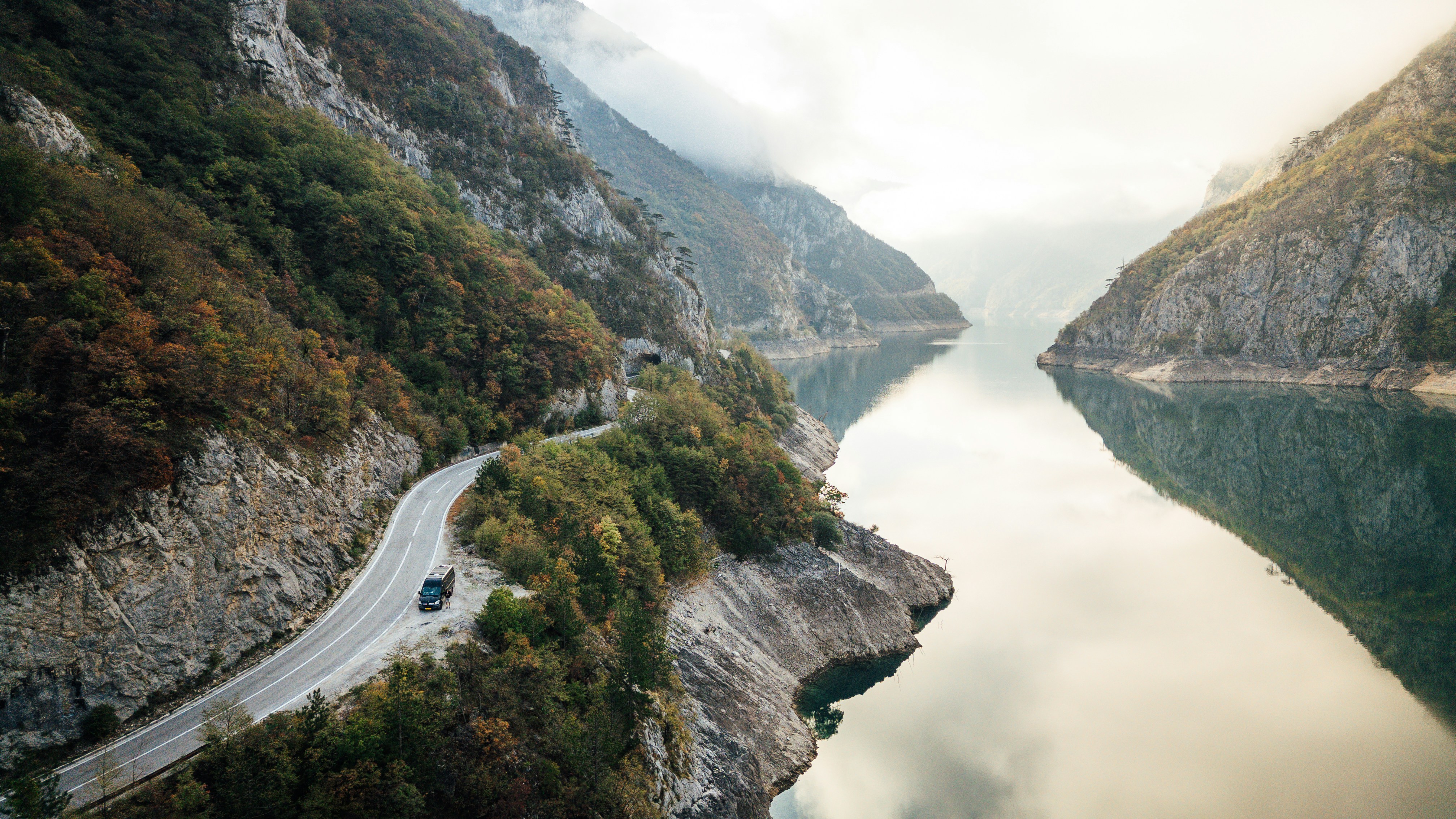 Curving road beside a calm lake in a mountainous landscape.