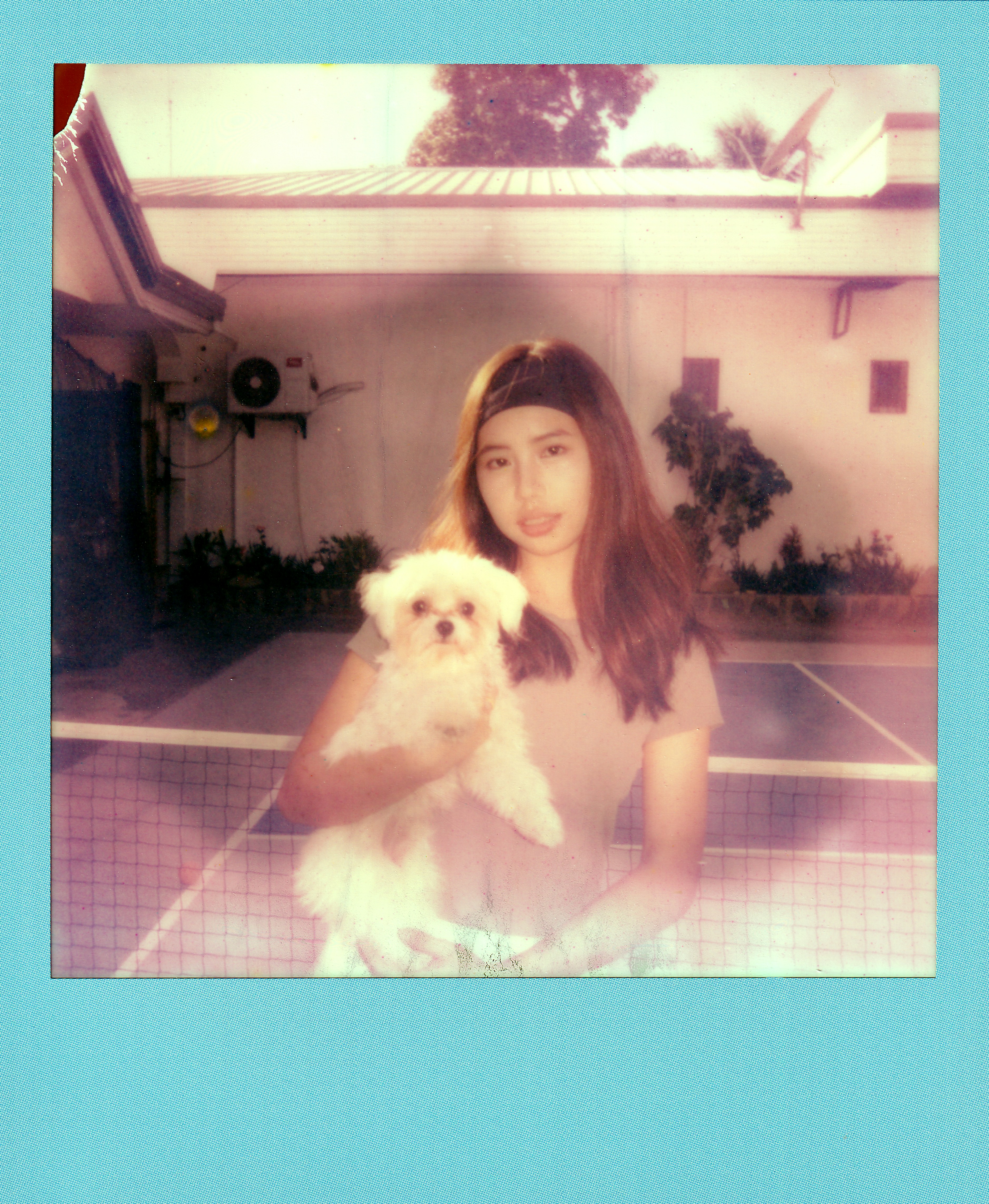 Young woman holding a small white dog outdoors