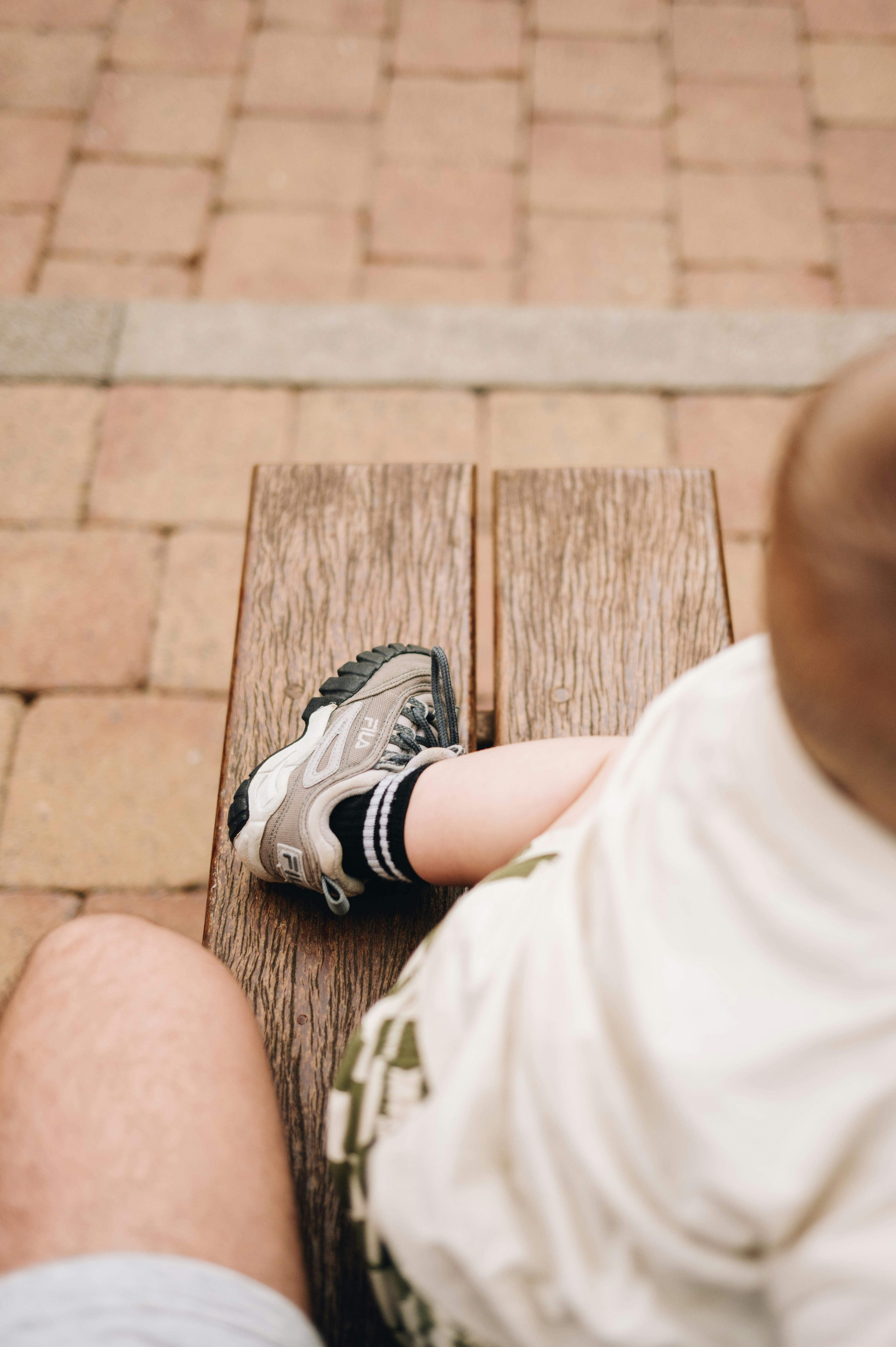 Child's leg with shoe on wooden bench