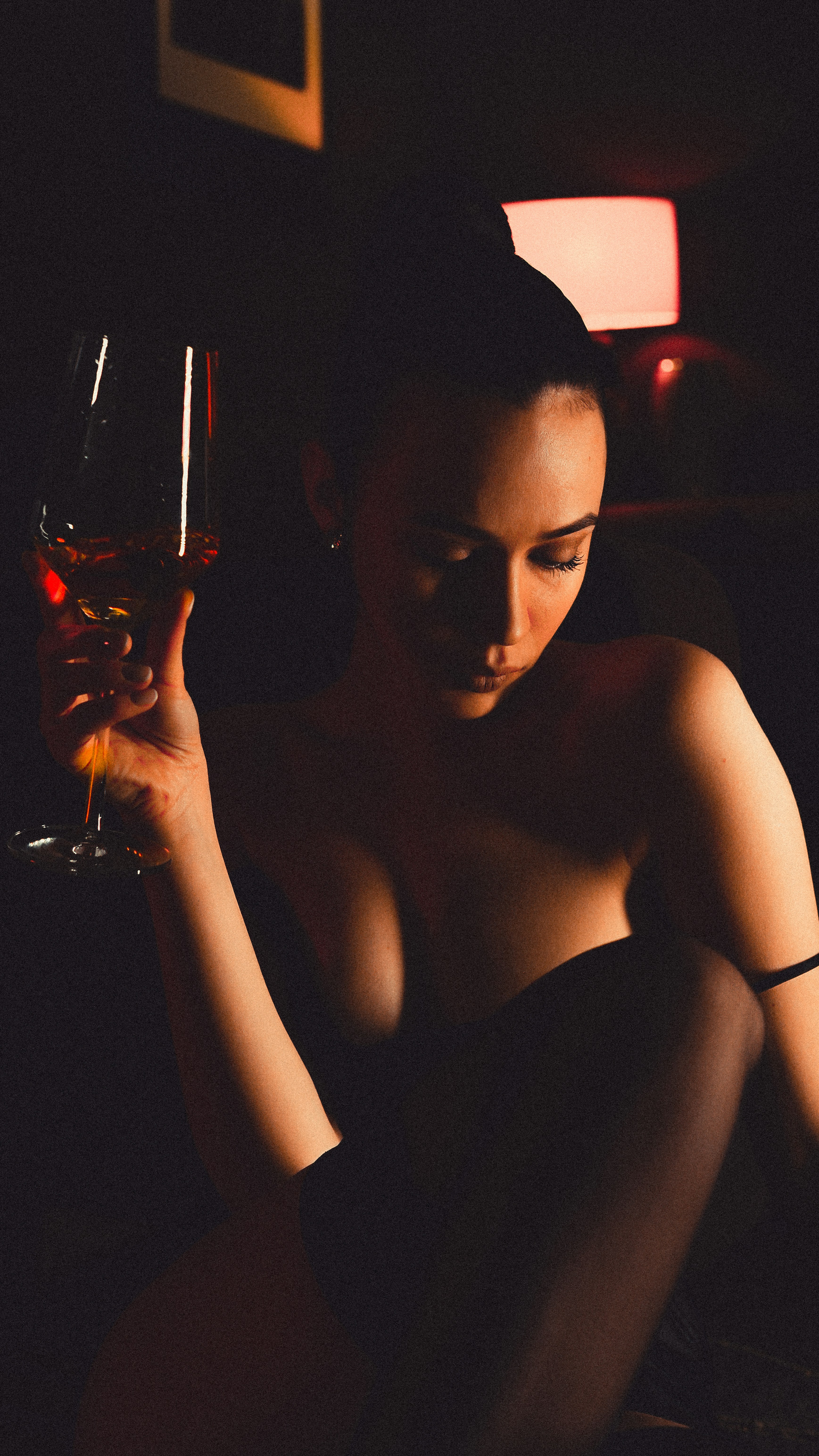 Eine Frau, die ein Glas Wein im schwachen Licht hält.