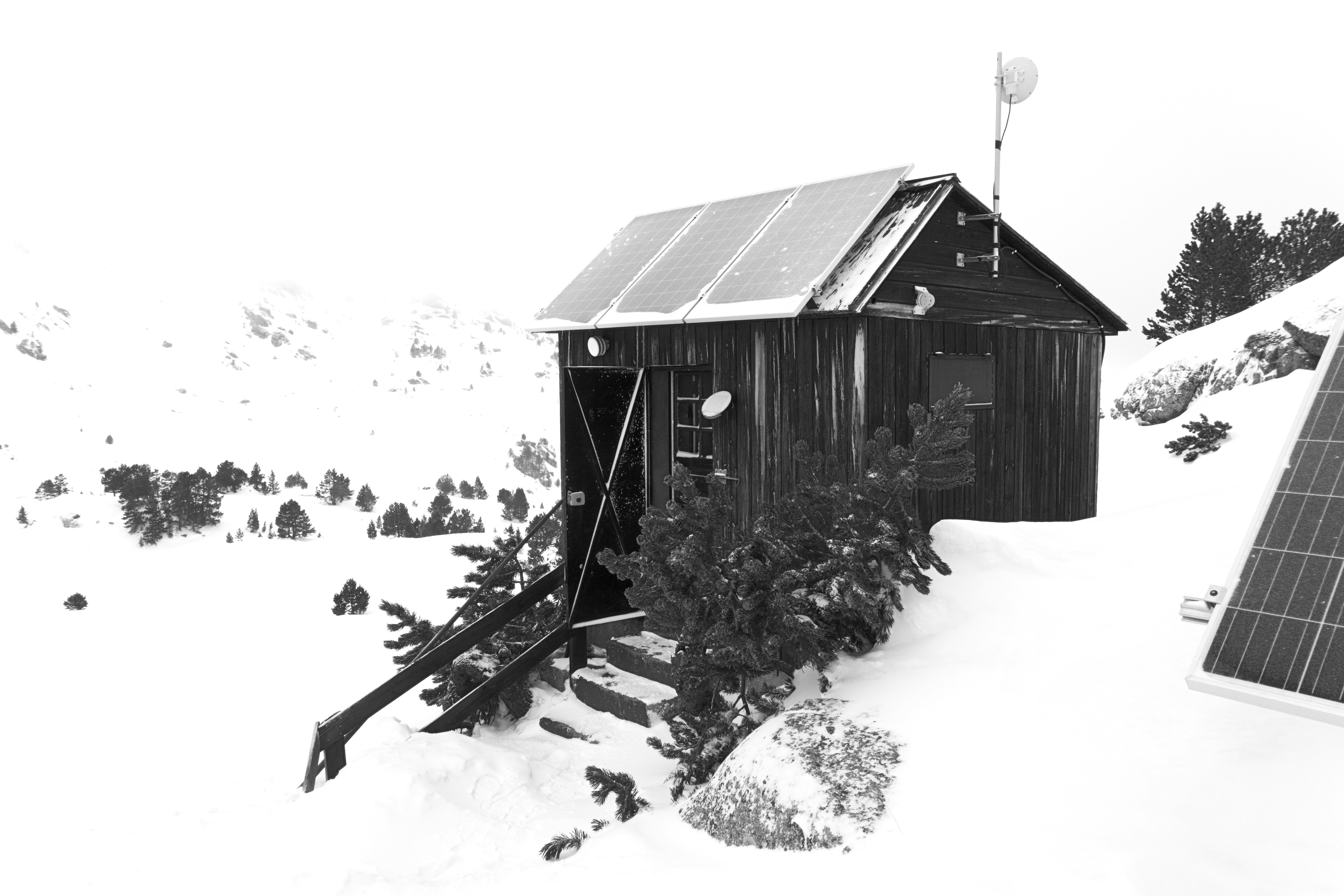Holzhütte mit Solarpaneelen in verschneiter Landschaft