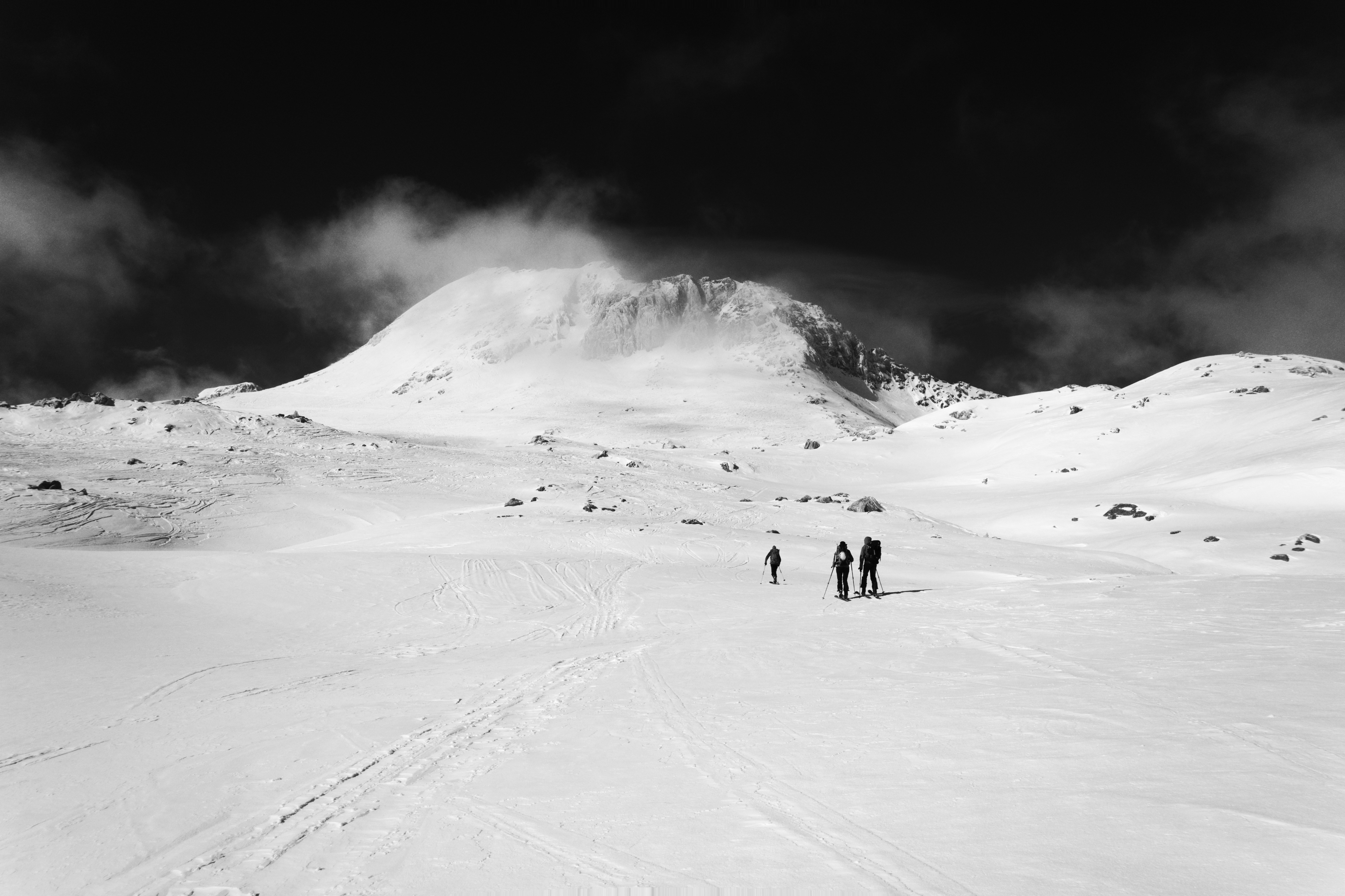 Wanderer besteigen einen schneebedeckten Berg unter bewölktem Himmel