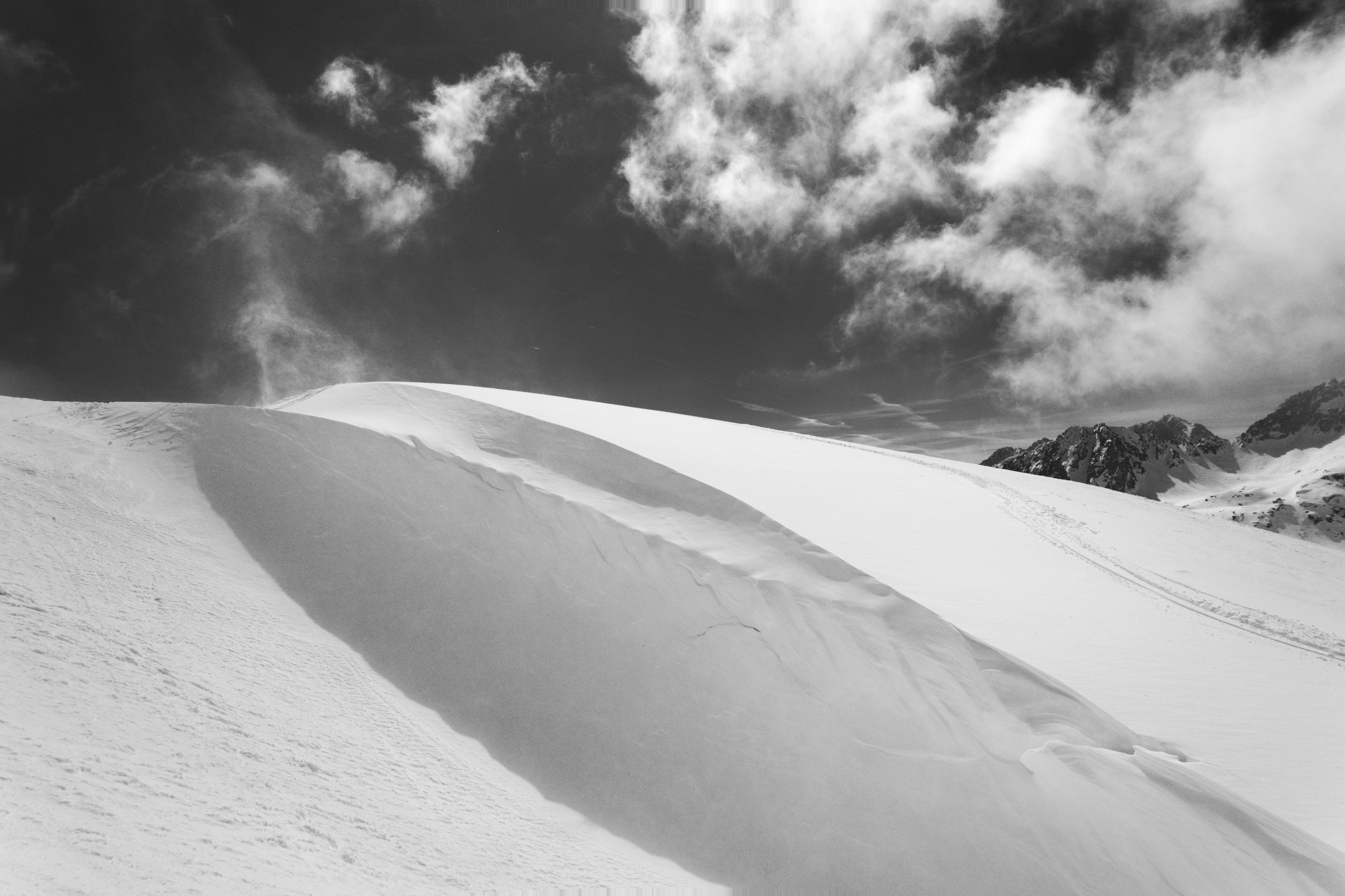 Schneebedeckter Berghang mit dramatischem wolkigen Himmel