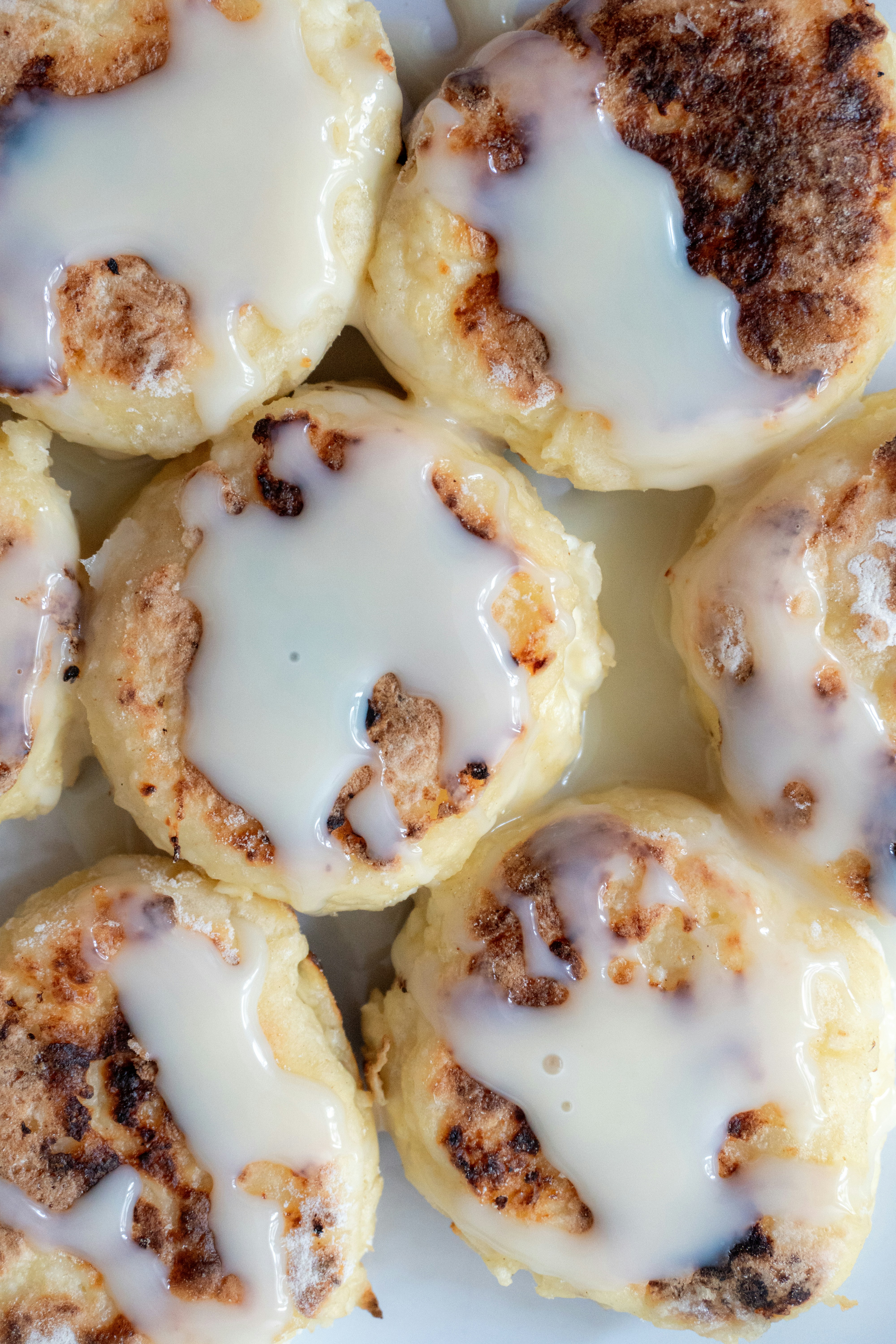 Close-up of syrniki drizzled with condensed milk.