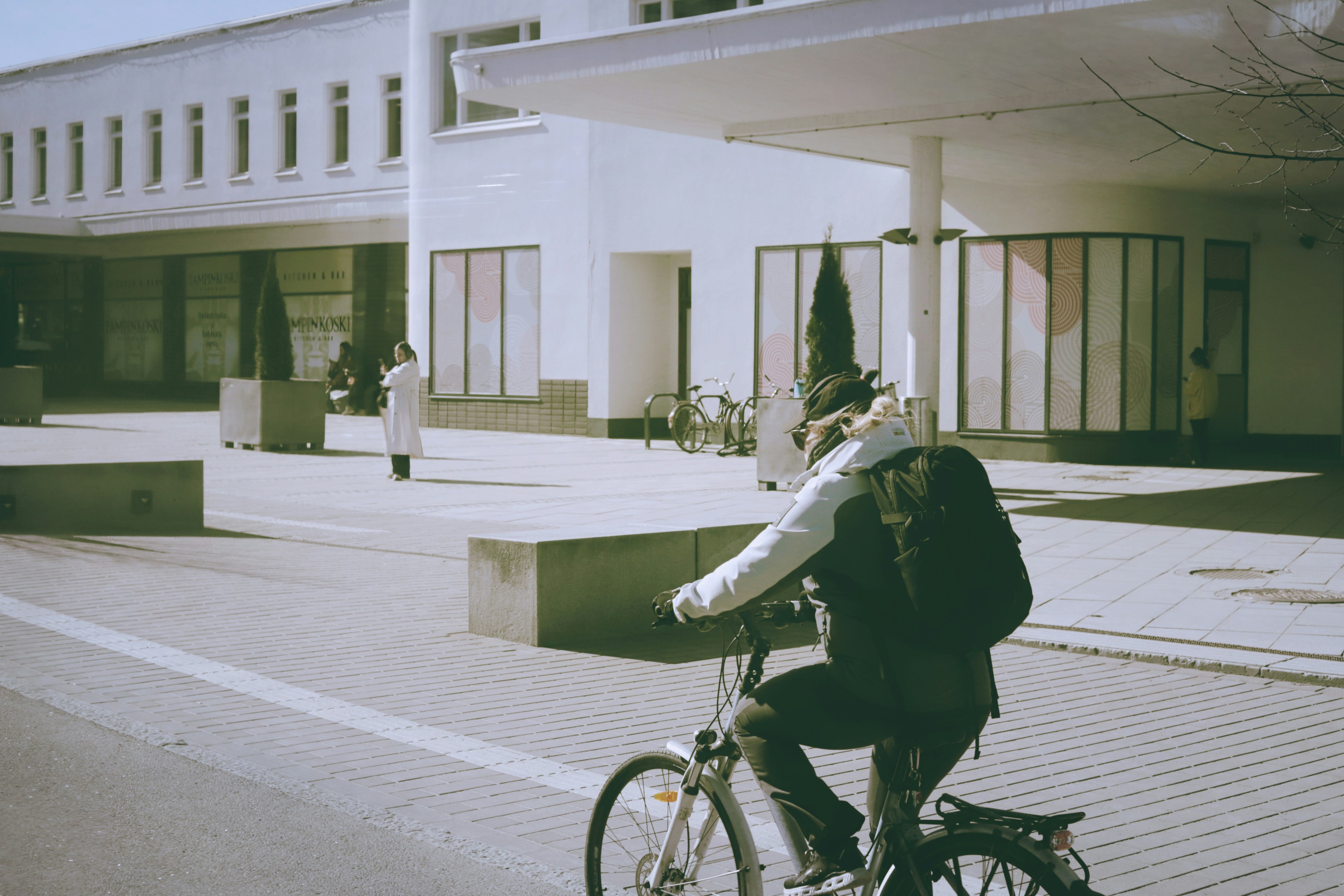 Person rides bicycle past modern building