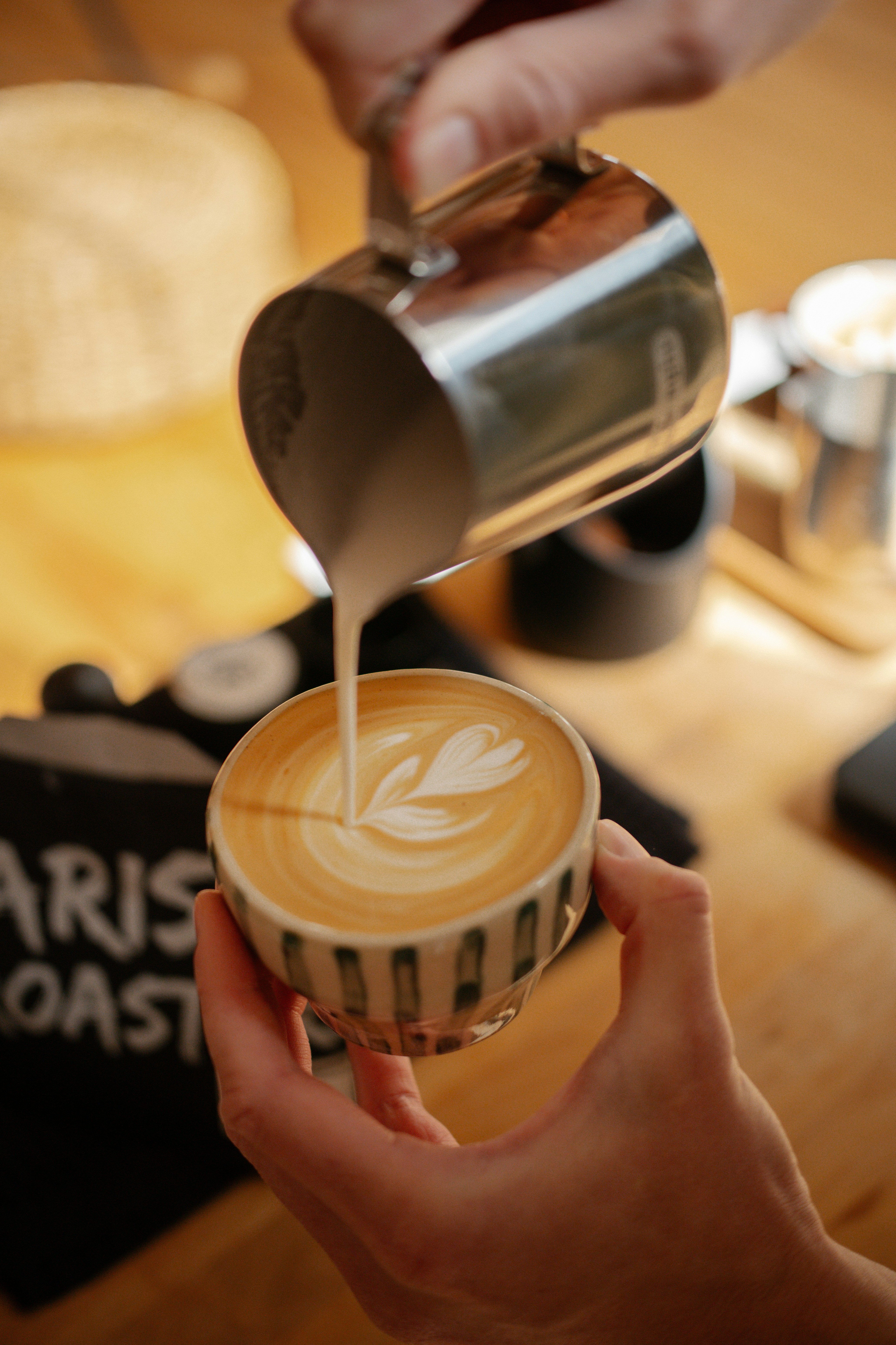 Barista pouring latte art into a ceramic cup