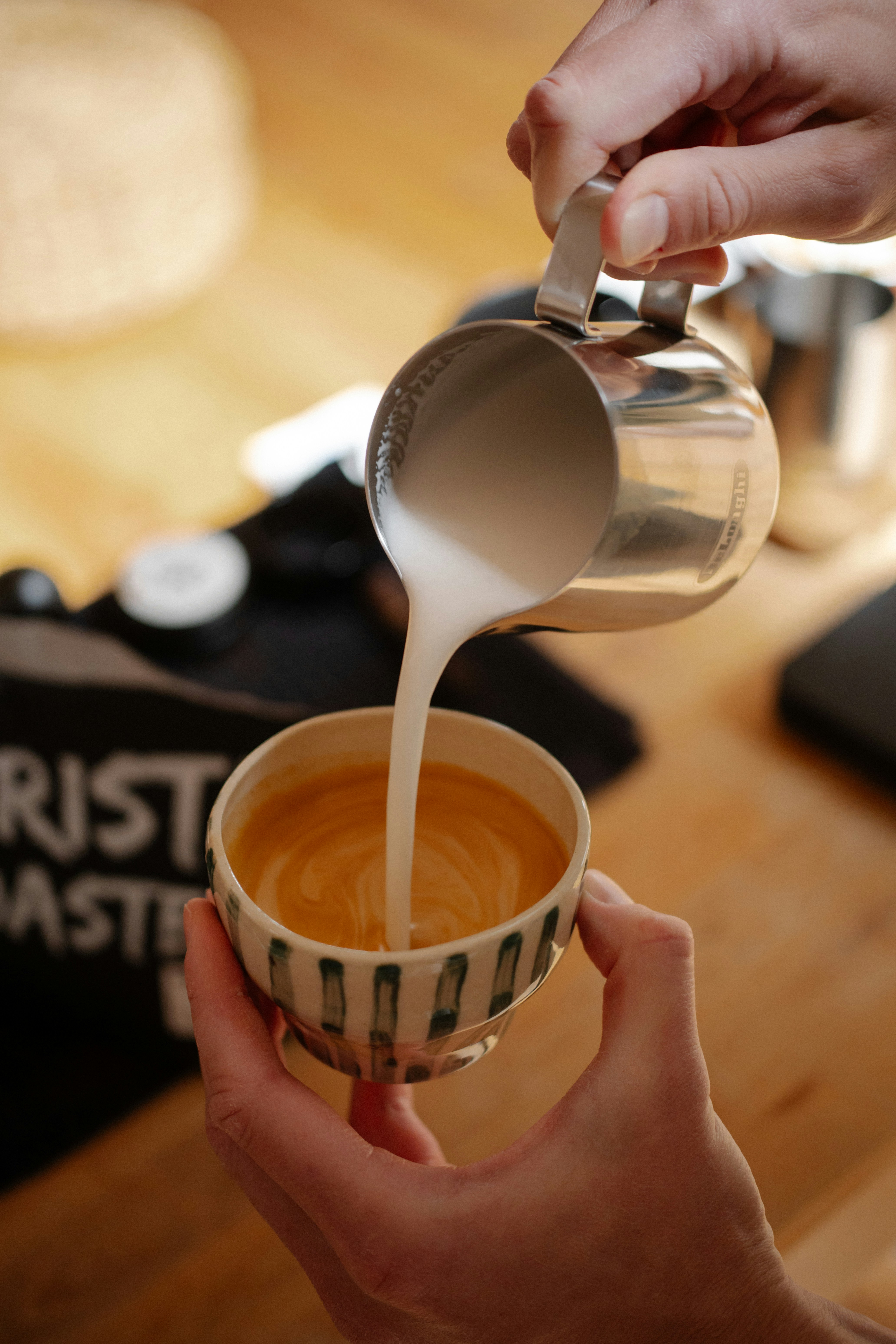 Barista pouring steamed milk into espresso for coffee