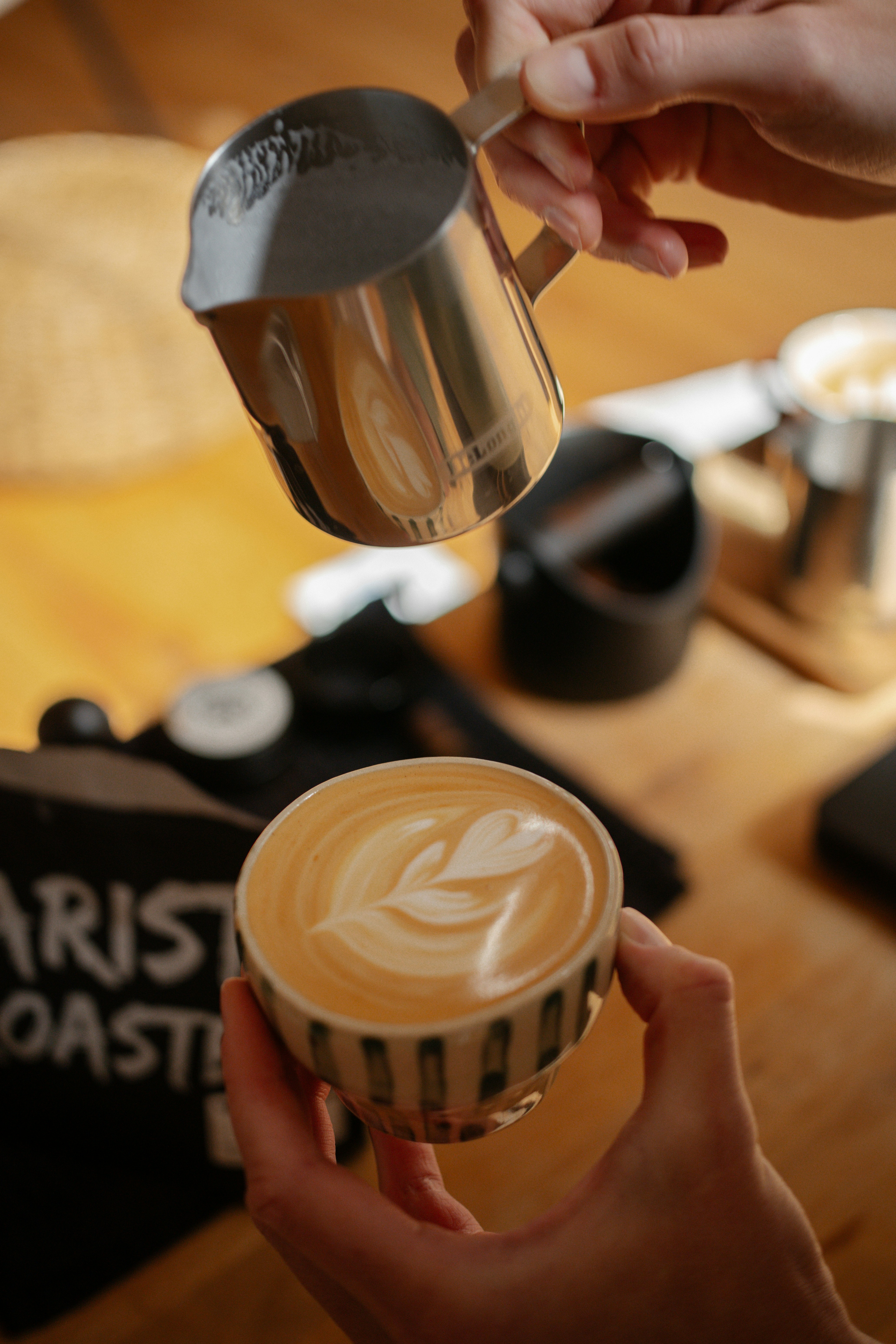 Barista pouring latte art into a coffee cup