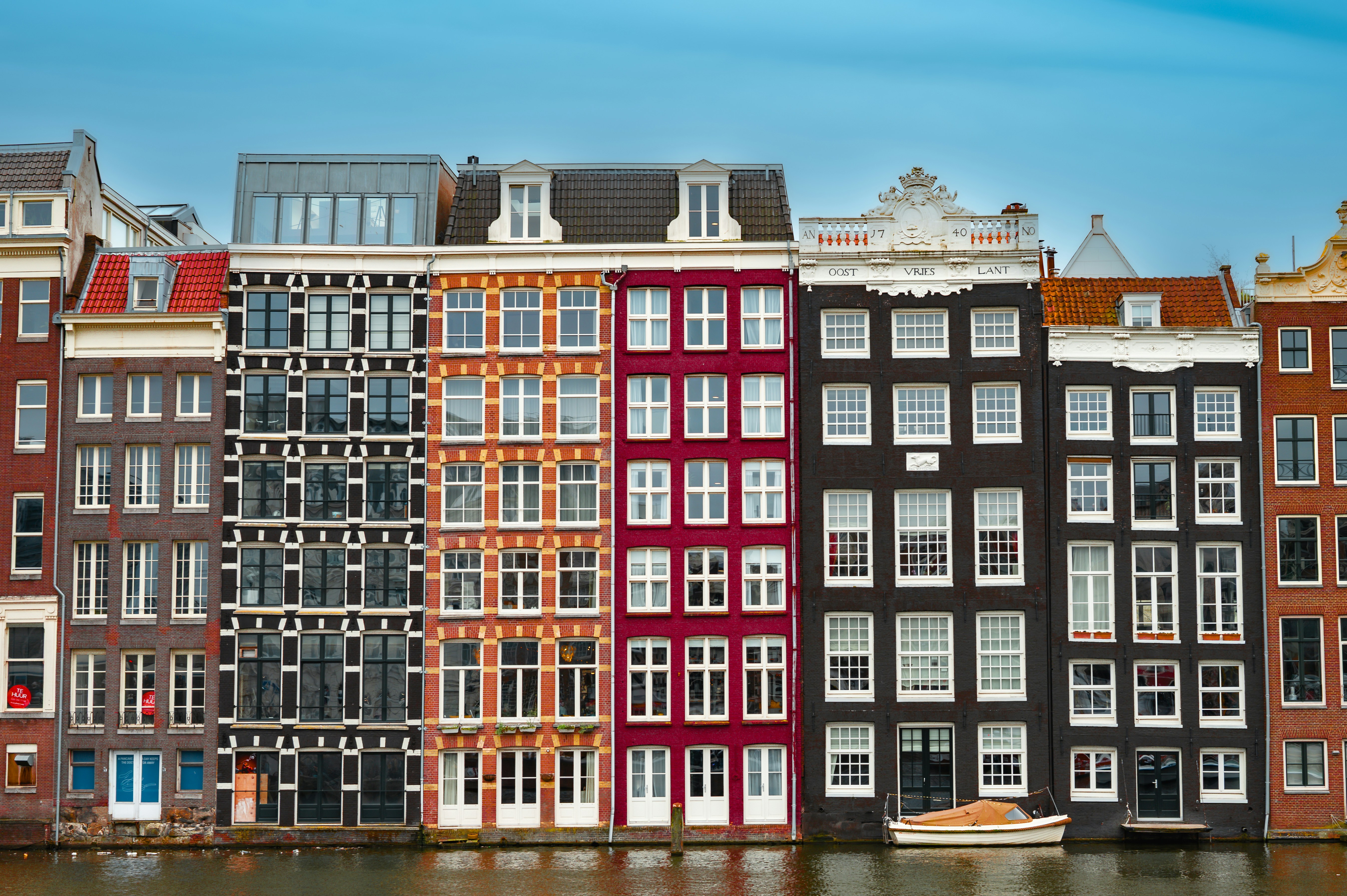 Colorful historic buildings line a canal in amsterdam.