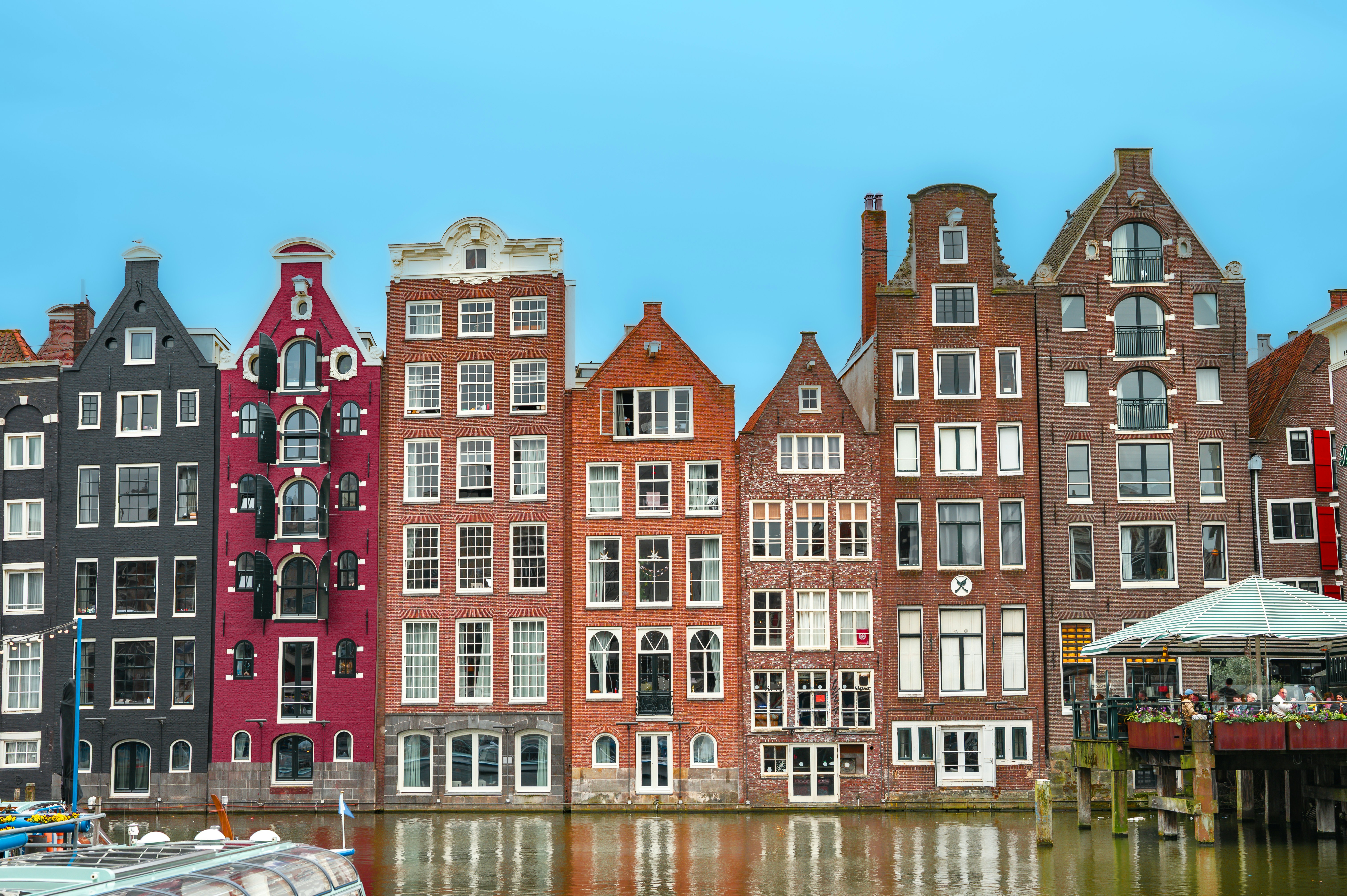 Colorful historic buildings line a canal in amsterdam.