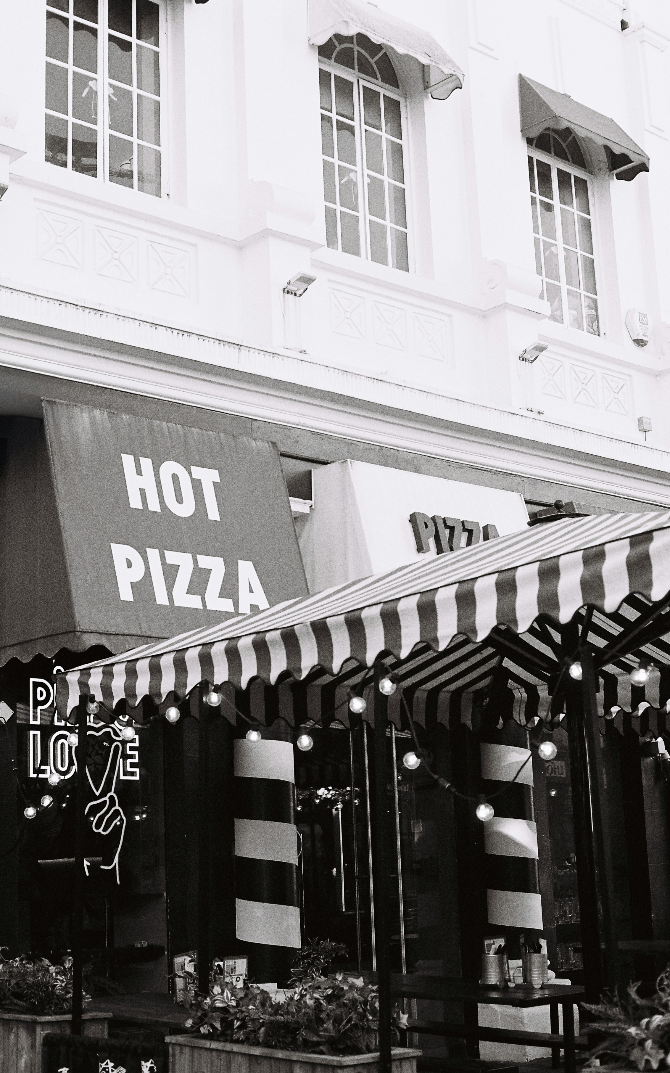 줄무늬 차양이 있는 식당 위의 뜨거운 피자 간판.