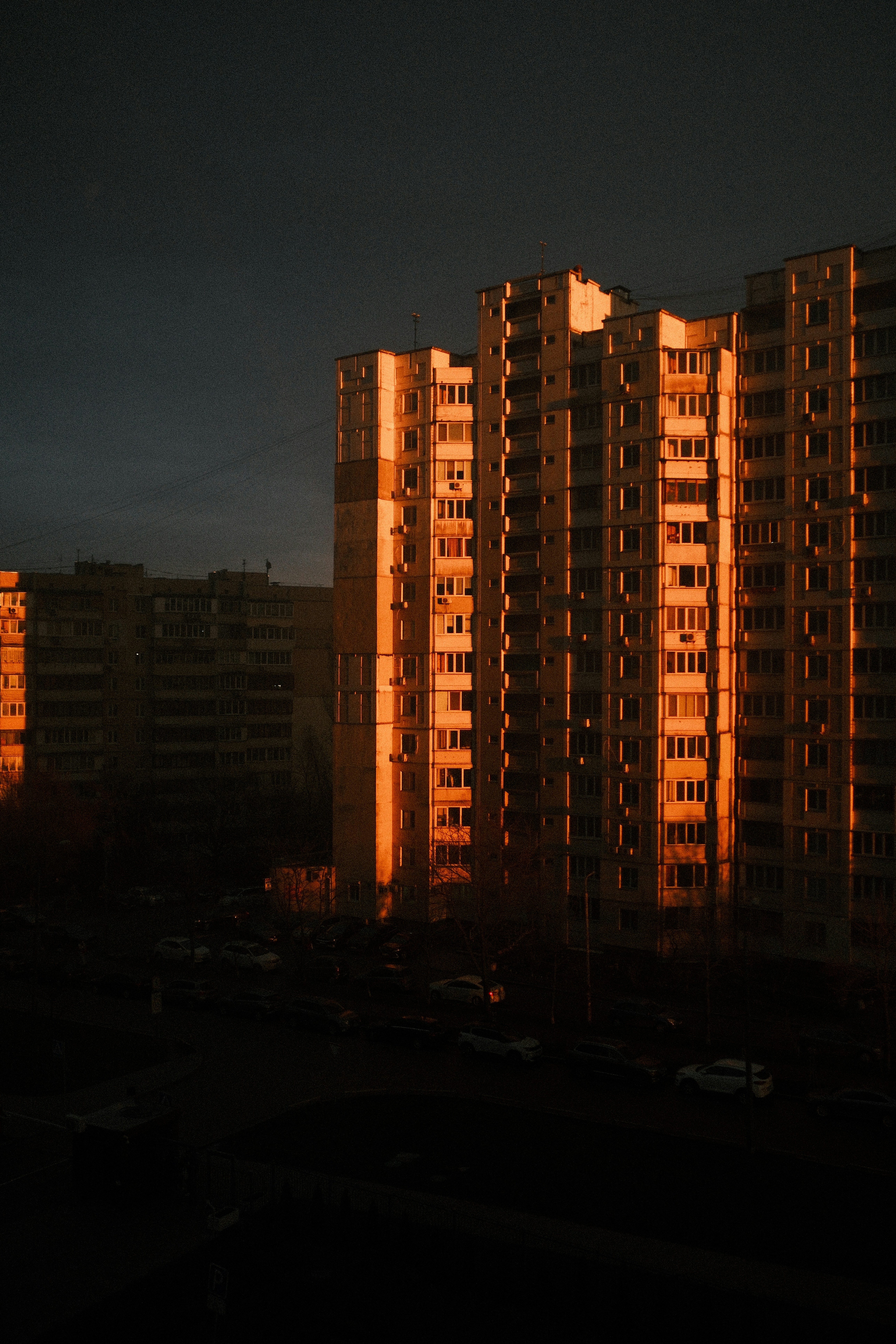 De hauts immeubles d’appartements illuminés par la lumière chaude du coucher du soleil.
