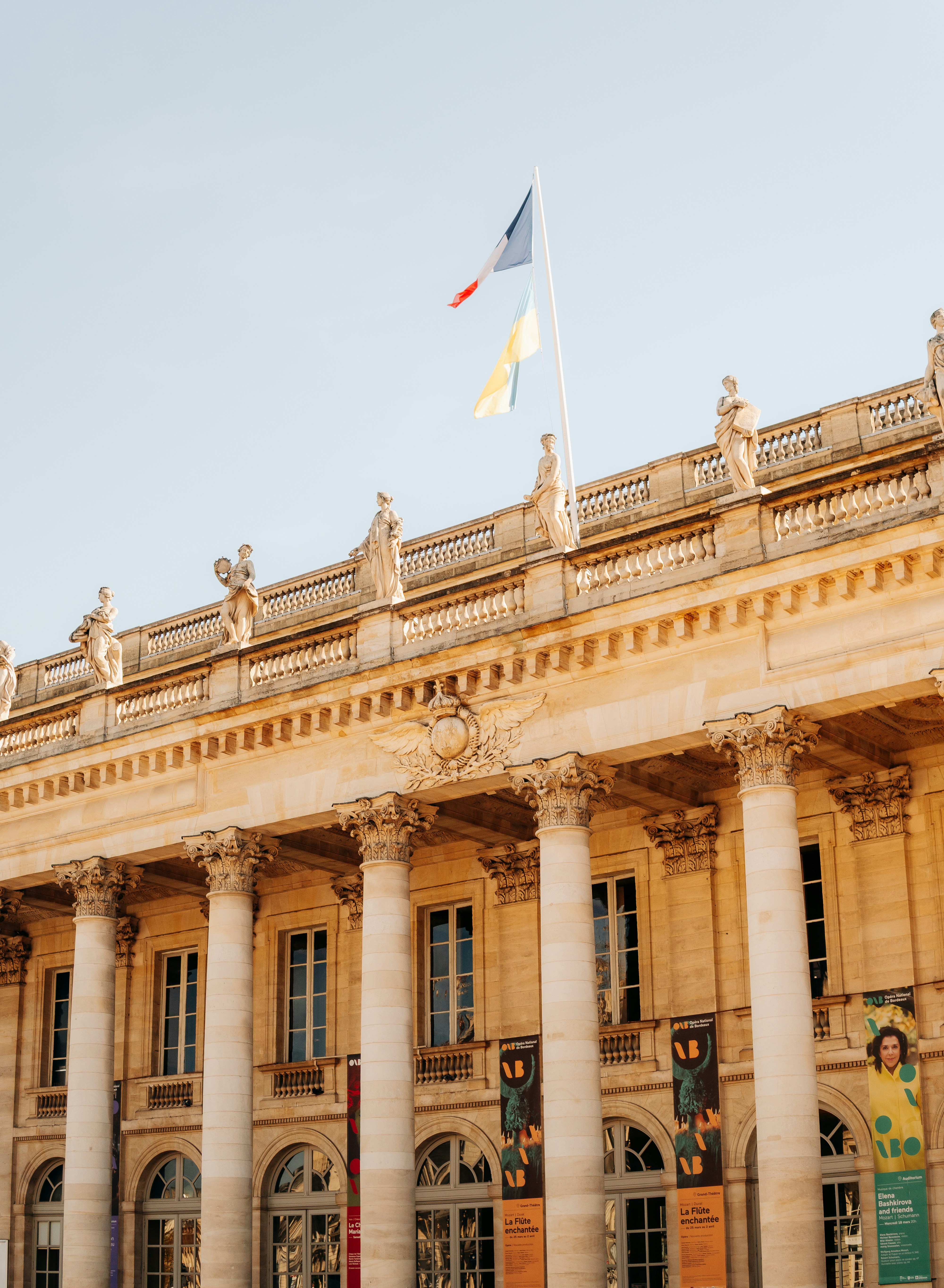 Grand building with columns and flags against sky