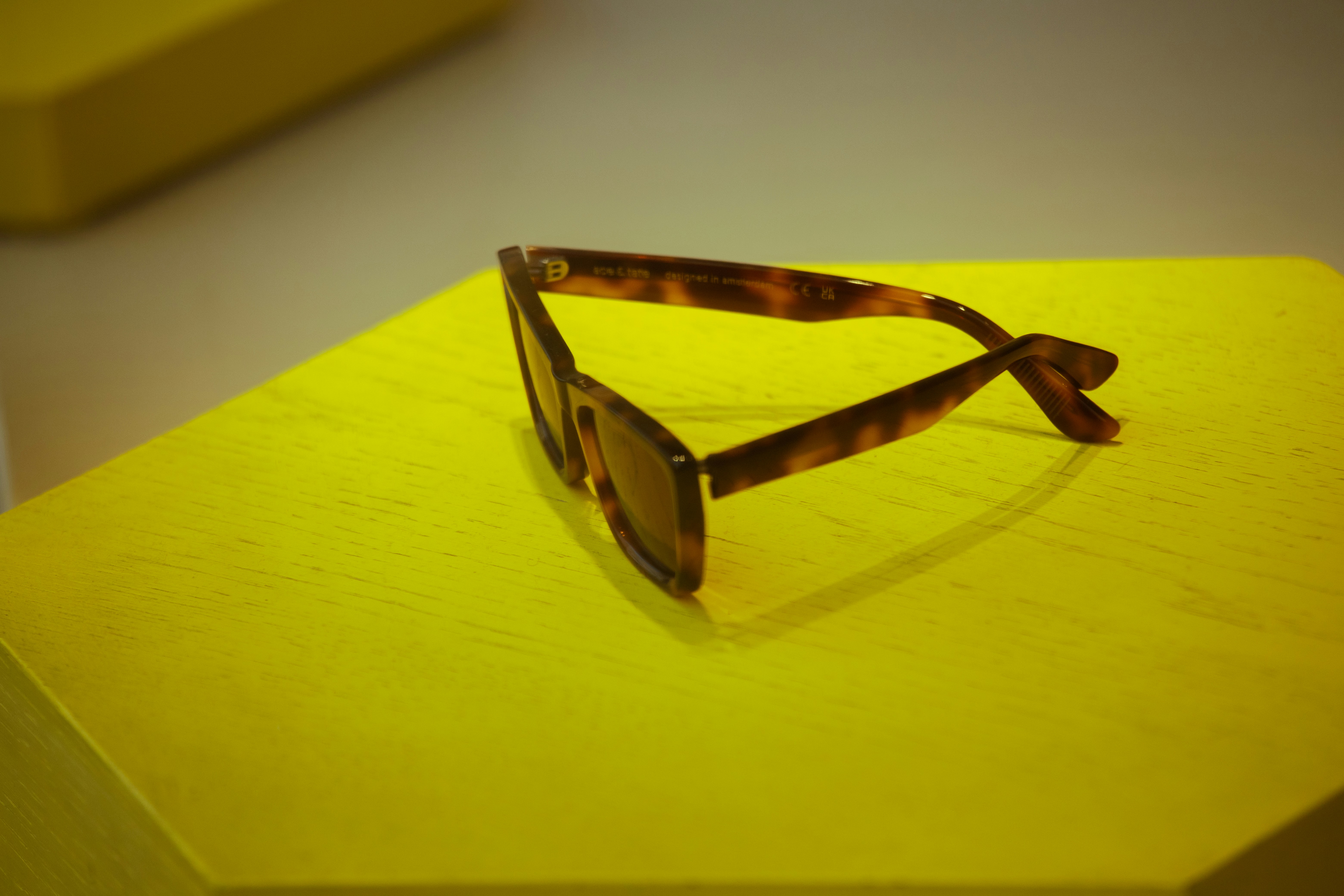 Gafas de sol carey descansando sobre una superficie amarilla