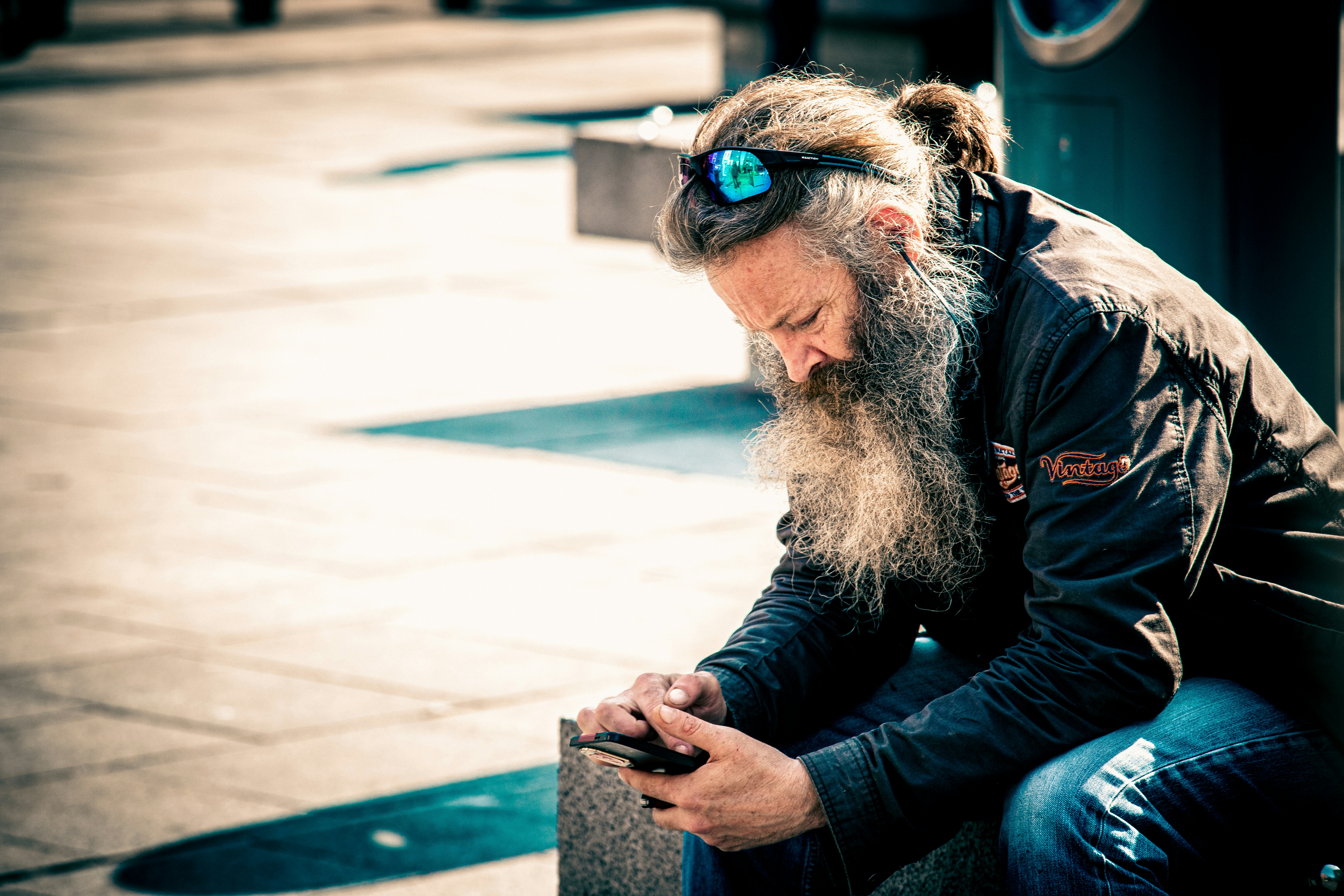 Man with long beard looking down at phone