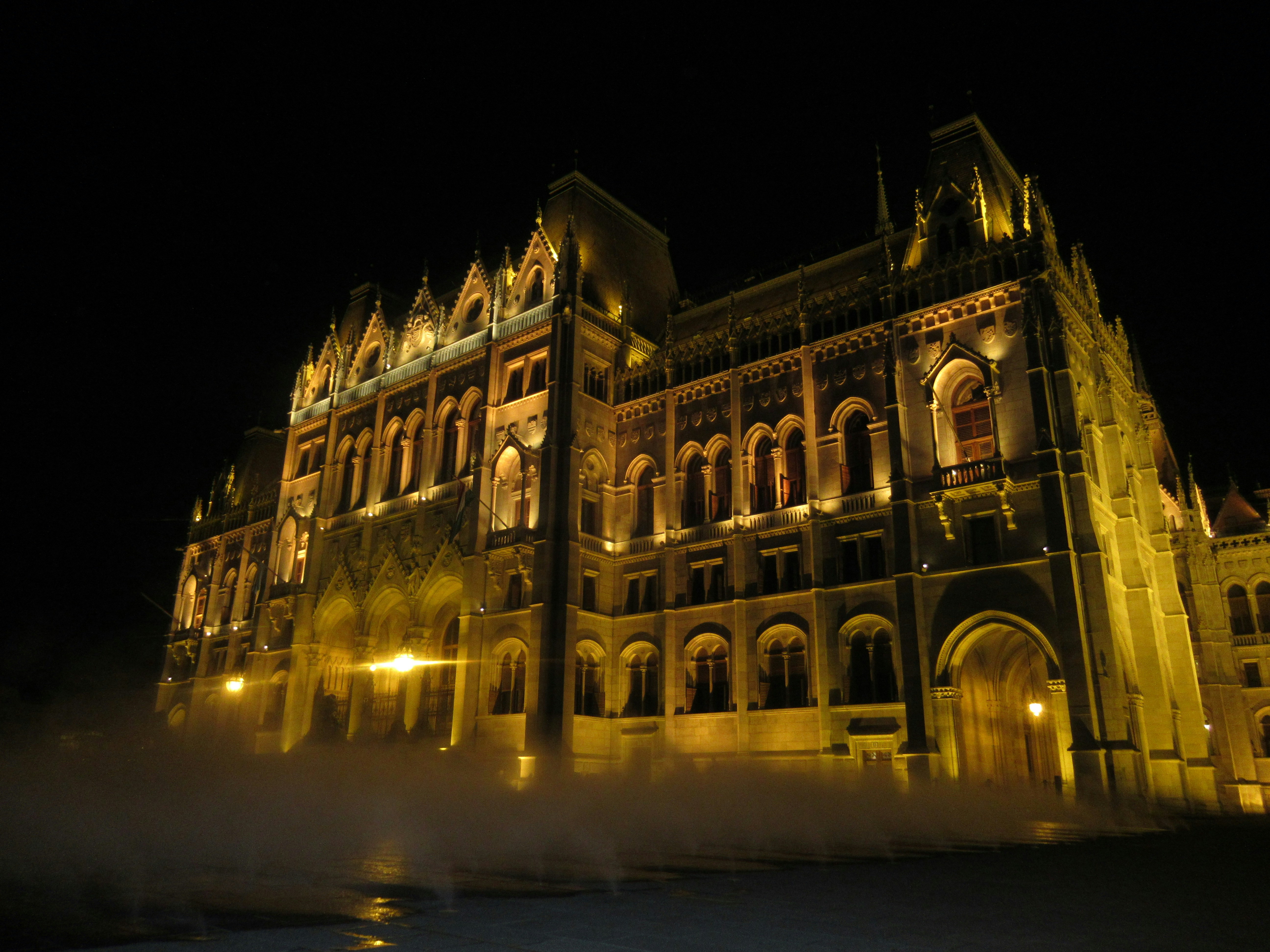Ornate building illuminated at night with mist rising