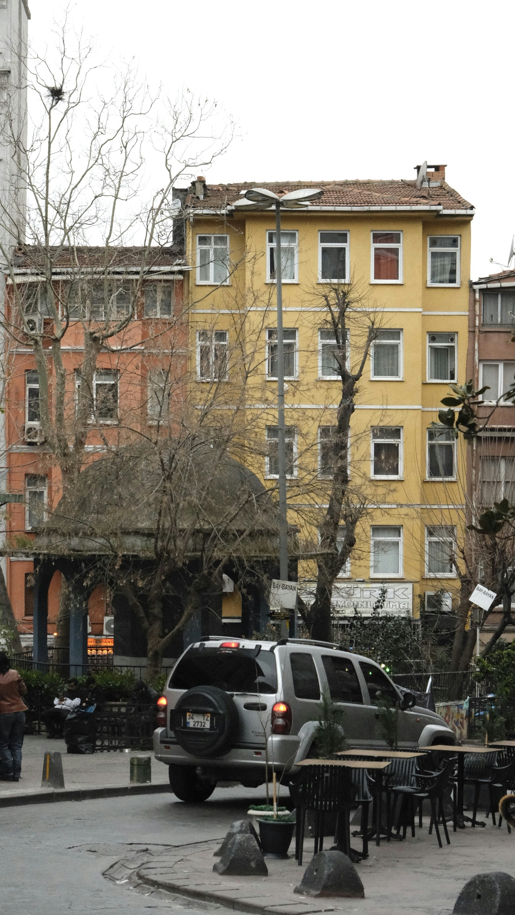 Silberner SUV parkte in der Nähe bunter Gebäude und Außensitzplätze.