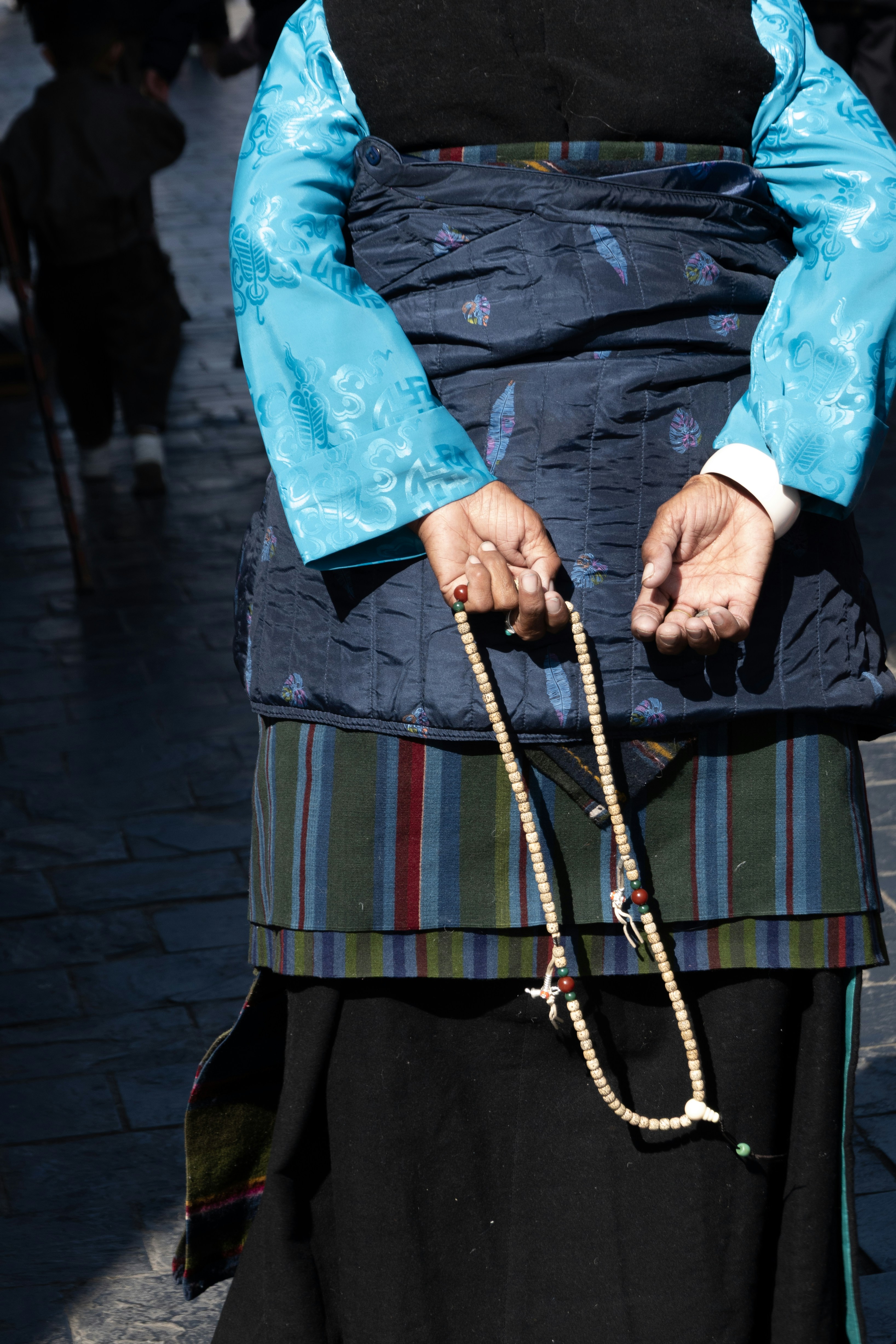 Person holding prayer beads with traditional clothing